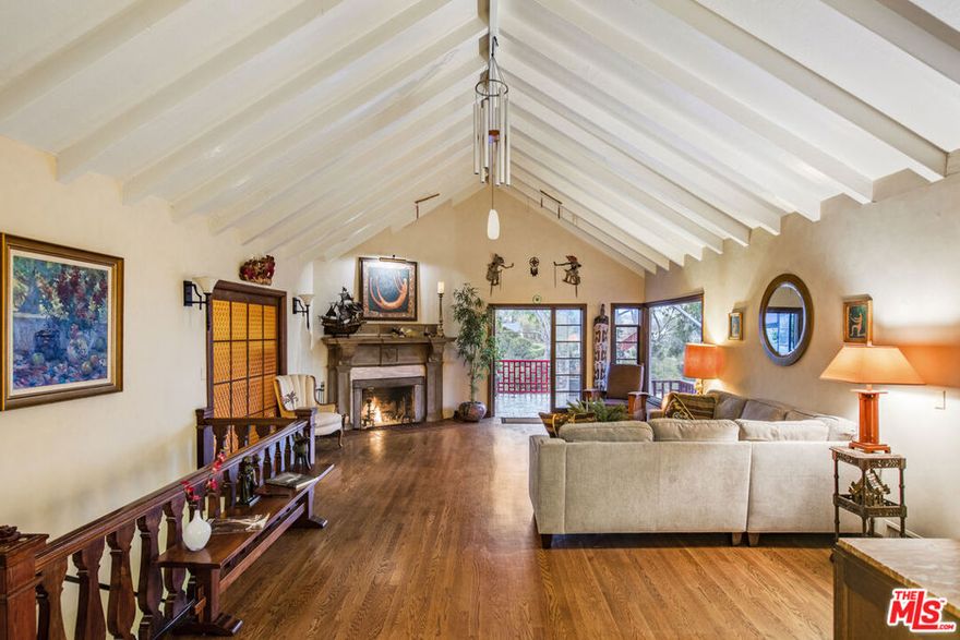 This magical estate, perched in the legendary Hollywood Hills, is a four-story architectural masterpiece and includes something very rare in the hills; when you step outside your kitchen door, it's onto your 6495 sq.ft. terraced, private park complete with fruit trees, a large raised bed vegetable garden, and cozy, private patios draped in shade by a huge 100-year-old oak tree. This is not just a home, it's a sanctuary above the fray, a living love letter to Classic Hollywood with a view of the iconic sign right outside your front door. Designed by acclaimed architect W. L.Schmolle and built by a renowned structural engineer, this 1948 castle blends timeless elegance with soul-stirring charm. Step through the front door and into a world of grandeur. Soaring 14-foot vaulted ceilings, a marble-clad wood-burning fireplace, and expansive picture windows open to panoramic views from Griffith Park to Long Beach. French doors lead you outside to a 400 sq. ft. entertainer's terrace with yet another fireplace, slate floors, and treetops swaying in the breeze. Every inch of this home whispers craftsmanship: hand-milled black walnut from Michigan, custom pocket doors, leaded glass windows, and subtle elements of Feng Shui which keeps the energy flowing freely. The chef's kitchen is a modern marvel with an Italian Bertazzoni range, stainless appliances, and ambient lighting that makes every culinary moment magical. Wander through one of the secret passageways and find yourself in the turret, a three-story tower where you'll discover an intimate lounge leading to a sun-soaked veranda, above that a circular meditation space and a bonus bedroom nestled beneath a skylight. Its like something out of a fairytale. The primary suite is expansive with views from every window, 2 large walk-in closets, and a Juliet balcony. The main bath has been completely redone, featuring dual marble sinks and heated floors. There is abundant storage space throughout the home, including a separate wine room complete with a 170-bottle EuroCave wine fridge. An 800 sq ft guest apartment with vintage O'Keefe & Merritt stove, clawfoot tub, and two private entries occupies the home's lower level offering even more opportunity for gracious living and creativity. Next to the property, a short walk down an historic stairway brings you to the charming Beachwood Village Square with its shops, market, and restaurant. Hiking trails to Lake Hollywood are right outside your front door, as well as access to horseback riding at Sunset Ranch. This is more than real estate. This is your storybook home! A private paradise.