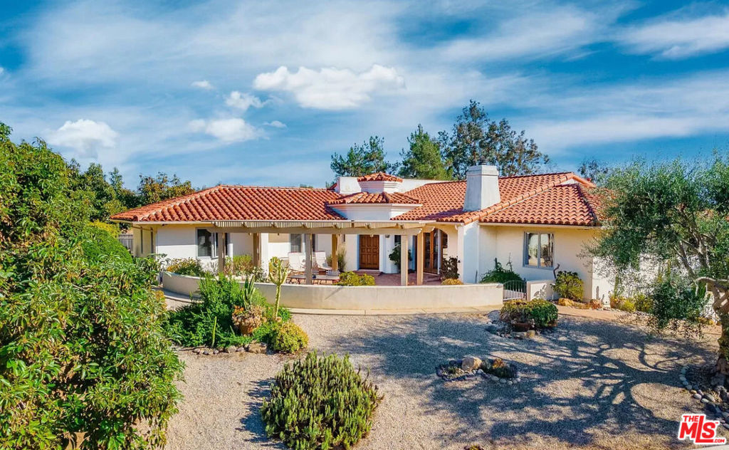 Welcome to this enchanting Spanish Revival estate tucked among citrus trees and lush landscaping in Fallbrook's prestigious Camino Cielo. This beautifully built and thoughtfully updated home features smooth stucco walls, a classic red tile roof, and fully fenced, manicured grounds with panoramic valley views. The property includes an exclusive private citrus grove, several mature avocado trees, and a paid-off solar field. Inside, discover 3000 sq ft of well designed living space with 4 bedrooms (1 currently used as an office) and 3.5 baths. Dramatic vaulted wood-beamed ceilings, graceful arches, classic Saltillo tiles, and brand-new luxury vinyl plank flooring bring warmth and timeless character throughout. The heart of the home is the newly remodeled chef's kitchen, featuring high-end stainless steel appliances, a 6-burner stove, custom cabinetry, timeless Calacatta quartz counters and a bonus dining area fireplace. Designed for entertaining, the layout includes a pool table game room connected to the main living area, flowing out to a spacious covered patio perfect for al fresco dining while overlooking the citrus trees and surrounding hillsides. These inviting outdoor spaces offers ideal settings for gathering with friends or enjoying quiet evenings and vibrant sunsets. The primary suite is a spacious retreat with dual walk in closets, a fully renovated luxury bath suite offering a walk-in shower, quartz counters, and refined finishes. Additional highlights include a separate laundry room/butler's pantry, dual fireplaces, an oversized garage with workshop, a versatile 300 sq ft flex room ideal for guests, fitness, or creative use, and even an above ground hot tub/spa. You'll love the gated entry, large driveway, extensive hardscaping, and RV parking with hookups . A truly special home that captures the essence of upscale Southern California country living private, refined, and rich with timeless charm. Schedule your private showing today.
