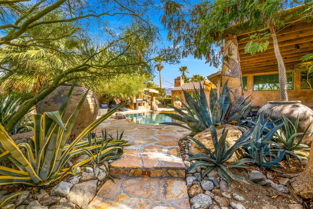 Extraordinary 6 bedrooms, 5.5 bath, 1.36 acre private desert oasis. Extremely secluded with private gates, cobblestone walkways, lush gardens, fountains, private pool, fire pits and stunning mountain views. The main house features an open floorplan with walls of glass, living area, gourmet kitchen with Italian appliances from Bertazzoni, and dining room with wet bar. The suites are arranged between three separate structures. The main house features 2 spacious bedroom en-suites each with doors to the pool. The detached 2 bedroom, 1 bath lower guest house has bedrooms three and four, and share a jack n Jill bathroom. A detached Casita has the fifth ensuite bedroom. A beautifully restored 1948 Spartan Aircraft Trailer measuring 25 feet is home to suite six, with a bedroom and full bath. The game room is in a temperature controlled garage, and features doors that completely open up the game room to the side yard, with ping pong, foosball, shuffleboard. The landscaping makes this hideaway feel like a private paradise, mature cactus, ficus, palms, trailing bougainvillea and the incredible mountains, all add to the magic of this very special property. Located in the exclusive Cahuilla Hills area of Palm Desert with El Paseo just a couple miles away. Theaters, spas, hiking trails, golf courses and tennis are also close by. No short term rental restrictions.