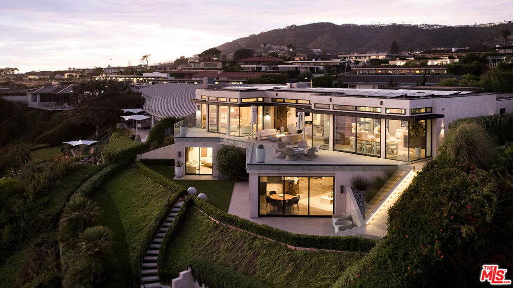 Featured in The Wall Street Journal | Discover a masterpiece of modern architectural innovation with this extraordinary oceanfront estate situated on a premier bulkhead lot with approximately 84 feet of ocean frontage. The endless coastal views, including Catalina Island, the Ritz Carlton, Dana Point Headlands and beyond, are nothing short of extraordinary. Located within the exclusive, 24/7 guard-gated community of Monarch Bay, this address serves as a passport for those who crave a life of unparalleled luxury and escape from the ordinary.Residents enjoy complimentary access to the newly remodeled Monarch Bay Beach Club. Managed by the Waldorf Astoria, the club offers dining and social events, along with beach attendants for complementary towel, beach chair, and umbrella service on the sand. Due to the community's leading edge security technologies, level of privacy, proximity to airports, direct beach access, and multiple amenities, it's a place where every aspect of modern living is thoughtfully catered to.Entering through the tall wood entry doors, you'll immediately be entranced by the explosive visual spectacle of uninterrupted ocean vistas and a courtyard with a sparkling pool and spa. Inside, the open floor plan exudes an air of relaxed sophistication. Wrapped in expansive floor-to-ceiling Fleetwood windows and sliding pocket doors, the home is bathed in natural light and nightly sunsets. The heart of this home is the sleek and modern Boffi kitchen equipped with SubZero and Wolf appliances. Other premium features include custom lighting displays, imported Zimbabwe stone countertops, magnificent hearths crafted from Armani stone, and electric shades that grace every ocean-facing window and door. Located on the main-level, the large primary suite features a spa-like bathroom with Taj Mahal countertops, Kallista sinks and plumbing fixtures, a soaking tub with ocean views, a walk-in shower, two water closets, and two boutique-like walk-in closets. Also on the main level are two guest bedrooms with ensuite baths and a powder room. Descend the floating staircase or ride the custom elevator down to the lower level, where you'll find a half bath, an entertainment area, a lounge with stone hearths and custom shelving, a bar adorned in black Zimbabwean stone, and an enviable custom office with ocean views. Adding to the allure of this residence is a cutting-edge smart home system, built-in outdoor seating around a firepit, a three-car garage, solar power system, and custom flush HVAC registers seamlessly integrated throughout the home.