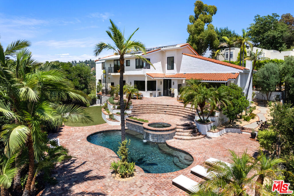 Located on the private, gated Oak Pass Road, one of the most charming streets near Beverly Park, this chic Spanish home blends classic character with a fresh contemporary aesthetic. Just minutes from the Beverly Hills Hotel and world-class dining, it offers resort-like living in a prime location. An expansive open floor plan is filled with natural light from floor-to-ceiling windows. The chef's kitchen with top-tier appliances flows into the dining and family rooms, while the spacious living room offers seamless indoor/outdoor access. The primary suite features a fireplace, sitting room, walk-in closets, and a balcony with stunning canyon views. Outdoors, a private oasis awaits with a pool, spa, fire pit, lush landscaping, and dramatic vistas. A separate guest apartment includes its own living and sleeping areas, bath, and sauna. A rare chance to live in a peaceful retreat that feels worlds away yet is moments from it all.