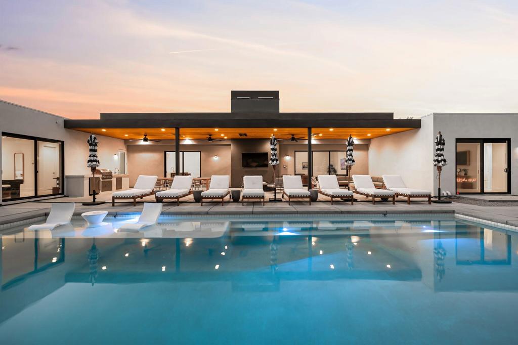 Located within the exclusive, gated Polo Villas community, this stunning 4,458-square-foot estate offers the pinnacle of desert living. A true masterpiece, the home features 6 bedrooms, 6.5 bathrooms, and a dedicated media room, seamlessly blending modern luxury with timeless Old Hollywood glamour. The open-concept design and high ceilings create an airy, spacious feel, while clerestory windows flood the great room with natural light, enhancing its serene atmosphere. Step outside to your private resort-style oasis, complete with a fully-equipped outdoor kitchen, sparkling pool and spa, putting green, and a cozy fire pit--perfect for year-round enjoyment. The outdoor living area is outfitted with ceiling fans, heaters, TV and Sonos speakers for comfort, regardless of the season. Inside, the gourmet kitchen, media room, and expansive bedrooms with large format tile ensuite bathrooms cater to both relaxation and entertaining needs. This home is designed for convenience and luxury, offering an EV charger, solar energy system, dual washer/dryer sets, and smart home features. Approved for short-term vacation rental in La Quinta, it presents a unique investment opportunity while providing an ideal personal retreat. Whether you're looking for a high-end vacation home or a profitable investment, this property delivers exceptional style, privacy, and desert elegance. It's truly the ultimate desert getaway.