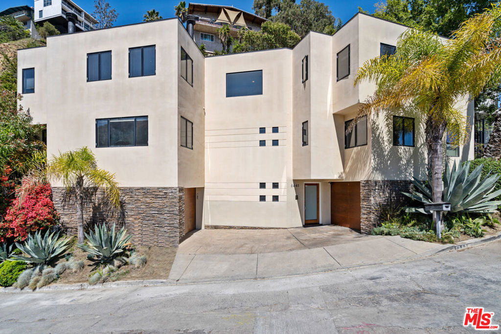 This sleek 3 bedroom + den/office contemporary home sits high above the street and affords city views from a very private setting. An open floor plan on the public level includes a large living room with fireplace and dark maple floors, an office/den, dining area, and very sleek, cooks kitchen featuring high end Thermador stainless-steel appliances, and caesarstone counters. The second floor bedroom level has expansive views to the west and opens to a large, sunny, landscaped terrace with spa. Master suite includes a glamorous bath, big, walk-in cedar lined closet, a fireplace, and views. Minutes to Lake Hollywood, the Hollywood Bowl, restaurants, shops, and the buzz of Hollywood. New carpet and paint.