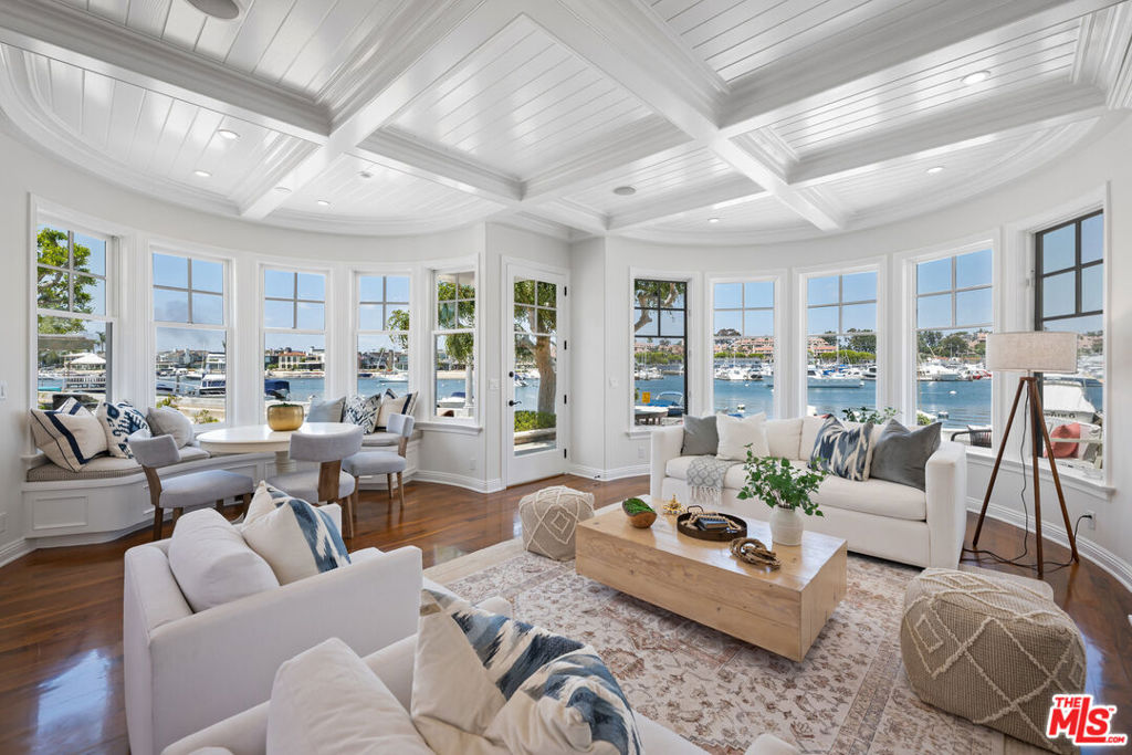 Welcome to waterfront living at its finest in this classically beautiful home located on Balboa Island in Newport Beach, CA. This stunning property boasts panoramic views of the North Bay Front, offering an unparalleled coastal lifestyle. As you step inside, you are greeted by the warmth of walnut hardwood floors, a curved staircase, and coffered ceilings, which add a touch of sophistication to the interior. Custom casework around the walls of windows enhances the home's charm and character, creating an ambiance of timeless elegance. Inspired by the homes of Cape Cod and the Hamptons, the exterior and interior of this home exude coastal chic with rounded bay windows and custom built-ins, creating a harmonious blend of classic and contemporary design elements. Every detail has been thoughtfully curated to create a warm and inviting retreat. The Primary Suite epitomizes luxury living with two ocean view balconies, where you can unwind and soak in the sights and sounds of the island. With high coffered ceilings, plantation shutters, abundant custom built-ins, a walk-in closet, and a spa-like bathroom featuring a dual vanity, vaulted ceilings, and an ocean view while showering, this Suite is a dream. Additional living spaces include two spacious bedrooms with walk-in closets, providing ample room for family and guests, as well as a versatile 4th flex room that can serve as a den, office, or guest bedroom, along with a Rooftop Deck with attached loft space. Perfect for a workout space, private office, or artists retreat. The kitchen is a chef's dream, featuring an island, gas cooktop with vent, and Wolf Double Oven, perfect for culinary creations and entertaining alike. Ample counters and cabinet space are complemented with a walk-in pantry an d appliance bar. A Dutch door off the built-in kitchen office area adds a touch of charm, while the Dutch Entry Door with beautiful leaded glass welcomes you home in style.Convenience meets luxury with amenities such as a laundry room with a sink, a ground floor full bath with exterior access, a 2-car garage with EV, a central vacuum, and abundant storage, including easily accessible storage in the attic. This home is the perfect place to relax or enjoy the fun of California beach living. With a large entertainer's patio and a beach right in front of the house (including a transferrable beach mooring & boat), you can enjoy the best of all worlds, whether it's lounging in the sun, taking a refreshing dip in the water, hosting boat parade parties or indulging in water sports right at your doorstep. Top it all off with a rooftop deck, where you can savor breathtaking sunsets, fireworks (that launch from the Dunes perfectly in front of the house), and panoramic views of the bay and beyond. This exceptional home on Balboa Island with its prime location (a short distance to shops, restaurants, the ferry, John Wayne Airport, and world-class Fashion Island), unparalleled views, and luxurious amenities, is a rare opportunity to own a slice of paradise in one of Newport Beach's friendliest and most enjoyable communities. Don't miss your chance to make this waterfront oasis your own and live the ultimate California coastal lifestyle.