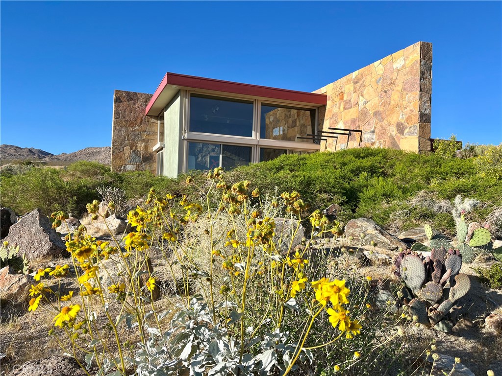 Villa Bajada—A Timeless Architectural Retreat in South Joshua Tree. Perched high near the Joshua Tree National Park boundary, on two contiguous parcels totaling 4.23 acres. Live with nature in this superb mid-century style modern gem while creating your personal studio for art, music, meditation, and entertainment. The main house is a 2007 built 1181 square foot 2-bedroom, 1 bath home with kitchen, dining room, living room and garage. Nearby the home, an unfinished 1108 square foot building flex space / art or yoga studio, featuring central HVAC, bathroom, another room and garage, plus in-ground pool—an opportunity to complete to taste with the original contractor still available and permit active. Surrounding the home, multiple patios and lush native landscaping create outdoor living spaces including a spa for moonlit dips and stargazing. This unique pied-à-terre makes a fantastic vacation getaway or a full-time residence or income / rental property. Rarely does a property of this vision come available. Villa Bajada is more than a home—it’s a living piece of art. Come experience this rare desert refuge now.