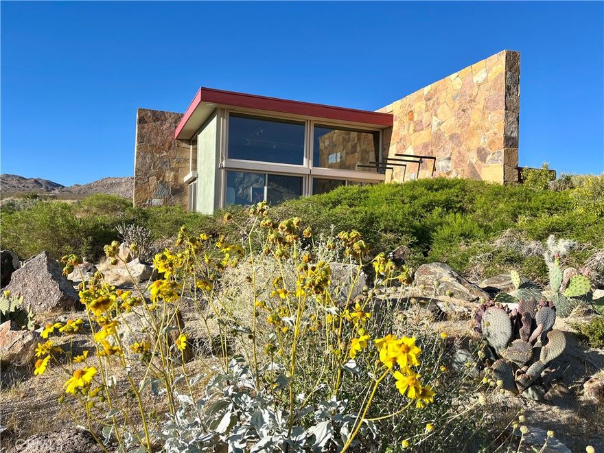Villa Bajada—A Timeless Architectural Retreat in South Joshua Tree.  Perched high near the Joshua Tree National Park boundary, on two contiguous parcels totaling 4.23 acres. Live with nature in this superb mid-century style modern gem while creating your personal studio for art, music, meditation, and entertainment. The main house is a 2007 built 1181 square foot 2-bedroom, 1 bath home with kitchen, dining room, living room, garage and features paid solar panels to reduce utility costs. Nearby the home, an unfinished 1108 square foot building flex space / art or yoga studio, featuring central HVAC, bathroom, another room and garage, plus in-ground pool—an opportunity to complete to taste with the original contractor still available and permit active. Surrounding the home, multiple patios and lush native landscaping create outdoor living spaces including a spa for moonlit dips and stargazing. This unique pied-à-terre makes a fantastic vacation getaway or a full-time residence or income / rental property. Rarely does a property of this vision come available. Villa Bajada is more than a home—it’s a living piece of art. Come experience this rare desert refuge now.