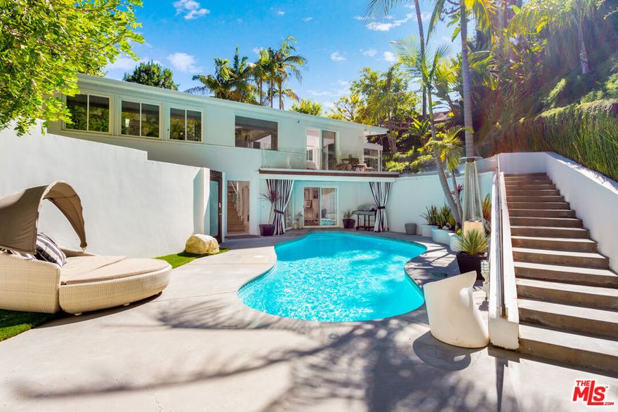 A very special "one of a kind" Mid-Century Oasis, and former home to several A-List celebrities. Nestled in a small cul de sac just 2.5 minutes behind The Beverly Hills Hotel, close to Sunset Blvd. This home has an incredible "vibe" , featuring an open floor-plan with excellent indoor/ outdoor flow and tons of natural light,  9 sky-lights, plus 3 oversized fireplaces. Large sumptuous Primary Suite w/  luxuriously appointed bath, plus 2nd bedroom both feature walls of glass which open out to a dramatic 50 ft. Waterfall, pond, lush yard & Fire Pit, with trails leading to hilltop Yoga area.  Updated newer Kitchen w/ porcelain counters, custom cabinetry, & top of the line MIELE appliances. Spacious, light-filled living & dining area set atop the trees. Downstairs features a private 3rd bedroom w/ separate gated entrance, perfect for guests, teenager, office or live-in. Media Den with Bar and fantastic sunken "conversation pit", around a fireplace, perfect for movie nights or friendship circles. Heated pool with new equipment glows from every room at night. Private and Tranquil with only 2 homes on street and ample parking rarely found in the hills. Private, walled and gated entry, ready to move in! This gem is an incomparable property and rare offering.
