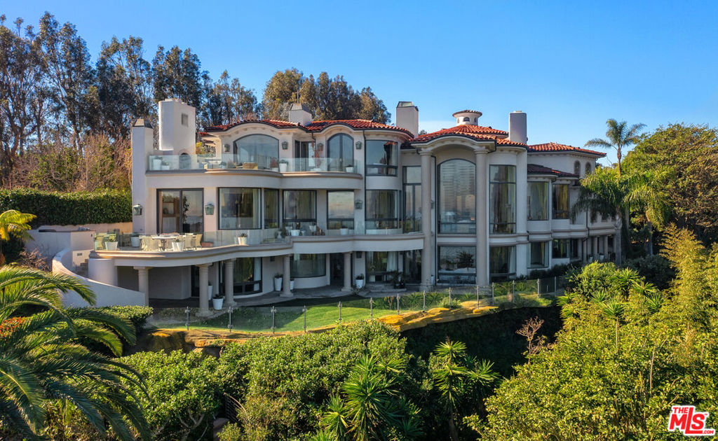Palatial in design and of a scale that cannot be replicated today, this ultra-private cul-de-sac estate commands gorgeous ocean, whitewater, and coastline views from its prestigious, geologically secure Point Dume bluff. Over an acre of parklike grounds for sumptuous living, including a private path to beach and multiple surf breaks! This grand oceanfront residence invites sumptuous entertaining and a lifestyle of harmonious luxury. Constructed on three levels to optimize the amazing views, the updated home has an elevator, dramatically high ceilings, soffit lighting, enormous curved windows, multiple fireplaces, and beautiful hardwood and limestone parquet floors. The property's front gate leads to a circular drive, where lush landscaping and a resort-style porte-cochre welcome visitors. Breathtaking views and bold sightlines begin at the front door, which opens to reveal a grand circular foyer with double-height ceilings, exquisite sweeping staircase, and a pair of tall columns flanking the entry arch to the living room and the views beyond. The living room has a huge fireplace, a serene piano alcove, and majestic floor-to-ceiling windows facing onto the ocean. French doors open to one of the home's view balconies for entertaining, al fresco dining, and relaxing under the stars. Two steps up from the living room is a beautiful ocean-view dining area. The chef's kitchen features a well-equipped butler's pantry plus a walk-in storage pantry, granite countertops, a large island, and top-quality appliances, including a restaurant-style Wolf range with a griddle top, and new Sub-Zero refrigerator, freezer, and wine cooler. An adjacent casual dining area steps down to a spacious ocean-view family room with a fireplace. This also opens onto the view balcony. Completing the main floor are an en-suite, ocean-view guest bedroom, an ocean-view office, and two powder rooms. On the upper floor, accessible by elevator or the central staircase, is the stunning owner's suite, with gorgeous views, fireplace, lavish marble spa-style bath, generous custom closets, and a large private balcony complete with fireplace and ocean-view seating. Also on the upper floor is another en-suite bedroom and an office/bonus/yoga room with a mirrored wall and an entertainment beverage station. On the estate's lower floor, in addition to three more ocean view en-suite bedrooms, is a mirrored gym, a powder room, laundry room, and a huge billiards/recreation room with a fireplace, wet bar, ocean views, and French doors opening to a large lawn that wraps around to the front of the house. The backyard entertaining area includes a covered patio, a view pavilion with an outdoor shower, and lighted steps all the way to the beach. The home has a two-car garage and a three-car garage, and has approved plans for updated outdoor hot tub/spa area. This spectacular estate is in every way equal to its magnificent setting: an inspired achievement for a Malibu lifestyle of tranquil luxury.