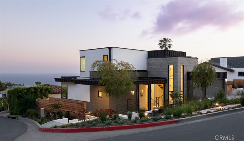 Perched above the iconic Laguna coastline, this brand-new 2025-built home offers the pinnacle of luxury living in Laguna Village. With approximately 4,200 square feet of thoughtfully designed space spread across three levels, this 4-bedroom, 4.5-bath residence seamlessly blends modern architecture with timeless coastal charm. From the moment you enter, you’re greeted by breathtaking panoramic views of the ocean, coastline, and horizon beyond. The open-concept floor plan is flooded with natural light and features elegant finishes, soaring ceilings, and a harmonious indoor-outdoor flow ideal for entertaining. The main living area centers around a stylish fireplace and flows effortlessly into a chef’s kitchen outfitted with premium appliances, a walk-in pantry, and designer touches. The expansive primary suite is a private retreat, complete with a luxurious spa-like bath, large walk-in closet, and a serene sitting area to soak in the ocean views. Three additional spacious bedrooms each offer their own en-suite baths, providing comfort and privacy for family and guests. Additional highlights include a dedicated family room, utility room, and laundry room, plus smart energy features such as central air, zoned cooling, heat pump, and solar power generation. The attached two-car garage provides convenience, while the home’s position on a 6,800 sq ft lot ensures privacy without compromising the views. Situated moments from Laguna’s vibrant village shops, restaurants, art galleries, hiking trails, and beaches, this 2025 new construction is truly a once-in-a-lifetime opportunity to own a modern sanctuary in one of California’s most coveted coastal communities.