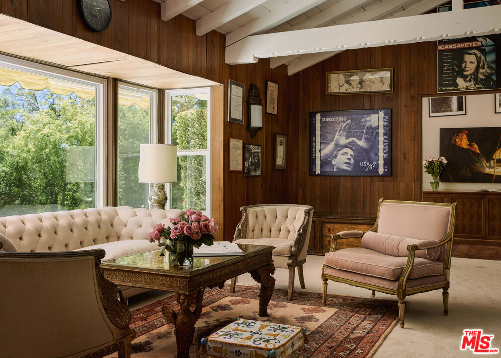 On the market for the first time in over six decades, this soulful 5-bedroom, 4-bathroom residence was the longtime home of legendary filmmaker John Cassavetes and acclaimed actress Gena Rowlands. Set on nearly an acre in the Hollywood Hills, the property spans approximately 4,305 sq ft and sits across three contiguous parcels totaling 37,992 sq including one buildable lot, offering rare future potential in this coveted location. A long, tree-lined approach leads to a classic traditional home with elegant Hollywood Regency details, gracious scale, and abundant natural light. The main level features formal living and dining rooms, a classic bar for entertaining, and a spacious bedroom suite offering flexibility for guests or creative use. Oversized windows frame views of treetops and natural greenery from every room, creating a serene and immersive connection to the landscape. Upstairs, the primary suite offers privacy and presence, while additional bedrooms are well-proportioned and thoughtfully arranged. Original architectural details remain intact, including a one-of-a-kind hand-painted bathroom artistic centerpiece created by a family member. The home is surrounded by nature and bordered by acres of protected county land, enhancing its sense of peace, privacy, and timeless retreat. This was not only a home, but a creative sanctuary where films such as Faces, A Woman Under the Influence, Minnie and Moskowitz, and Love Streams were conceived, edited, and in part filmed, contributing to the legacy of American independent cinema. A once-in-a-generation opportunity to own an authentic piece of Hollywood history.