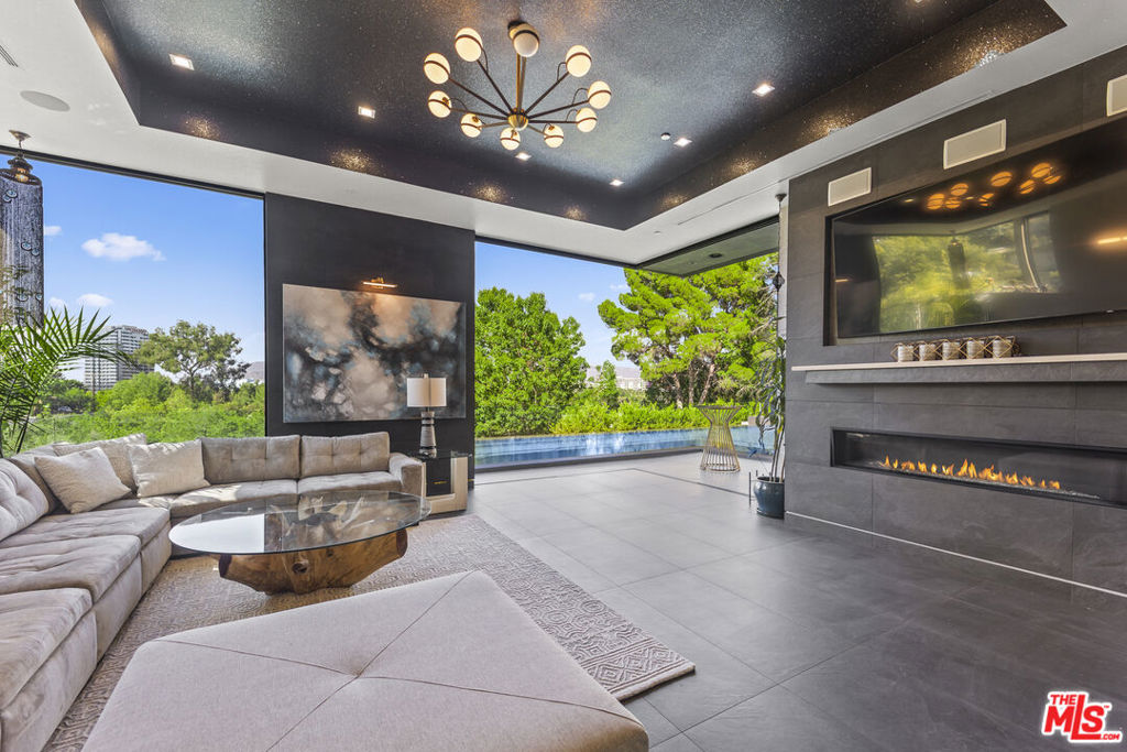 Set high in the Hollywood Hills, this designer estate by Alon Zakoot blends modern design with a twinkling of romantic Old World charm, offering privacy, sophistication, and the essence of a true California getaway. From its elevated perch, enjoy panoramic views with Universal Studios' iconic Harry Potter castle as your backdrop.Inside, timeless finishes meet artistic detail. Stone floors flow into a chef's kitchen with premium appliances, while handcrafted Moroccan lighting sets the mood in the dining space. The living room, crowned with a luminous ceiling and framed by retractable glass doors, opens seamlessly to the outdoors connecting to an oversized infinity pool suspended 20 feet above ground, lush gardens, and expansive entertaining areas.The primary suite offers a private sanctuary with a balcony, spa-like bath, and generous closet space. All six bedrooms feature unique details, private balconies, and outdoor privacy. A family room with direct access to the outdoor lounge invites effortless gatherings. This estate is designed for both comfort and entertainment, with an elevator, rooftop deck, outdoor kitchen, poolside BBQ, and resort-like greenery. An ADU adds flexibility for guests or extended living. More than a home, this is a lifestyle. Property was built in 2022.