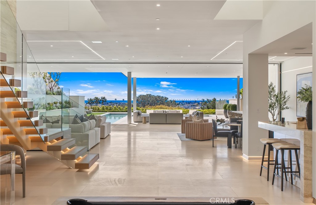 1119 Dolphin Terrace, a generational trophy property designed by Christopher Brandon showcases exceptional modern design and architectural excellence located in the heart of Corona Del Mar's coveted Irvine Terrace community. This meticulously crafted estate, taking six years to reach completion, spans approximately 10,200 sqft of pure luxury on a uniquely deep and expansive lot. This remarkable property boasts 5 bedrooms, including 2 primary bedrooms, and 8 baths, offering unparalleled comfort and sophistication. The interiors feature massive scale and soaring ceiling heights, creating a sense of grandeur that defines Southern California coastal living at its finest. Entertain with ease in the expansive living spaces, highlighted by a media wall with a jaw-dropping 219" LCD TV wall, a well-equipped bar + glass cellar, and two kitchens for culinary enthusiasts. Motorized pocket doors seamlessly blend indoor and outdoor living, leading to a spectacular 65' lap pool that invites you to relax and unwind while enjoying breathtaking ocean, jetty, Balboa, and coastline views. For those who prioritize health and wellness, the property includes a spacious wellness center offering full-size gym, sauna, steam room, and meditation area, ensuring a holistic approach to your total well-being. The attention to detail is evident throughout, making this estate one of the most captivating and exciting properties to ever be publicly offered for sale in Corona Del Mar. Additional features enhance the allure of 1119 Dolphin Terrace, such as its proximity to the Newport Beach Country Club and Fashion Island, placing world-class amenities at your doorstep. Enjoy the convenience of walking to Balboa Island and relish the central location within Newport Beach, providing easy access to the best that Southern California has to offer. This is not just a residence; it's a lifestyle statement, a testament to luxury living in one of the most desirable locations on the West Coast. Seize the opportunity to own a landmark property that transcends the ordinary, a true embodiment of Southern California's finest. Welcome home to 1119 Dolphin Terrace, where every detail reflects a commitment to unparalleled quality and refinement.