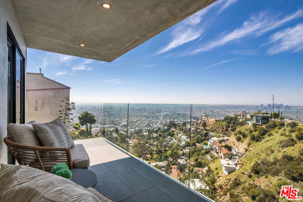 Magnificent jetliner views above the electric glow of Los Angeles a short distance from the Sunset Strip. One of the few with these types of views towards the Long Beach Harbor, LAX and the Santa Monica Bay. WALL to WALL windows. This home delivers unmatched value and views in one of L.A.'s most sought-after hillside enclaves. Blending sleek, contemporary design with natural serenity, this open-concept home features soaring ceilings with a seamless indoor-outdoor flow throughout. Go down the beautiful stairs into your enormous private primary retreat with your own patio. The primary suite occupies its own floor with spa-like bath, freestanding soaking tub, and glass-enclosed shower. Entertain or unwind on multiple terraces with frameless glass railings that preserve the jaw-dropping views. Smart home upgrades include motorized blinds and a built-in projection system. While officially listed as a 2-bedroom (easily restored), the current layout lives as a modern, light-filled 1BR suite with voluminous living spaces. A manicured path leads to a private backyard oasis perfect for a peaceful lounge, hillside garden, or future expansion. A beautiful home that makes you feel light and free. Sale includes two parcels (TMK 5556 015 058 & 5556 015 059). Video tour: https://vimeo.com/1069803280