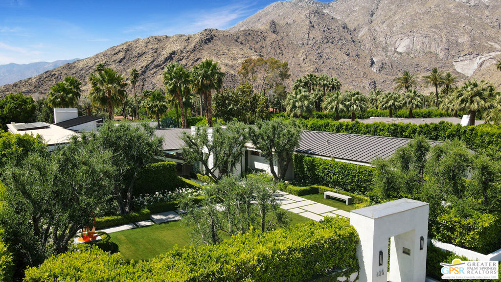 Welcome to this secure sanctuary suitable for 2 or 200! A very private celebrity retreat that is one of the few major ground-up remodels in the prestigious Old Las Palmas neighborhood. The main structure with 6,669s.f. was rebuilt by a General Contractor for his personal residence, equipped with the finest systems and deluxe world class amenities. Perfectly designed for art collectors and sculpture enthusiasts. The walled/gated pristine green grounds provide a tranquil palette for contemplation wrapped with mature olive trees, boxwood hedges, white roses with a black granite infinity reflecting fountain leading to the grand entry tower. The elegant foyer opens to an expansive vaulted living room with natural stone fireplace and terrazzo floors indoors and out. An adjacent media/morning or game room and fully equipped wet bar with window to the walk-in custom wine room. Fleetwood in-wall sliders maximize your indoor-outdoor experience. The ultimate jaw-dropping Chef's kitchen has Macassar Ebony African wood cabinets finished in eleven coats for elegant high sheen designed with Gullwing lifts, peg organized drawers. Double Sub-Zero side-side refrigerator/freezers, Wolf five burner cooktop plus Miele dual ovens/dishwashers, rapid microwave, vegetable steamer and two warmer drawers. Garden view pass-thru service window to the backyard poolside BBQ kitchen. The outdoor playroom is the HUB of the home featuring a heart shaped pool with spa/waterfalls, a boulder/waterfall with stream surrounded by mature fan palms and an outdoor bath-shower. The resort-like pool is wrapped by an elevated tanning deck, lounge areas and firepit feature. The main residence has a garden view guest suite with its own private patio, dual closets, and dual vanity bath. Another guest suite currently used as a home fitness center has a full bath, walk in closet which could easily serve as mother-in-law or staff suite. There is a large media room adjacent to the pool bath/changing room with a handicap design and dual showers, dual vanity, and storage closet. The 28-foot Primary is truly a suite retreat with double door entry, lounge style sitting room, full wall fireplace, unique 12-foot-tall window wall of sliders open to the patio/pool-spa and mesmerizing mountain views. Its pampering bath has a luxurious soak tub, separate steam/rain shower. Dual vanity with bird's eye maple cabinets, French faucets, a huge walk-thru closet and second laundry. A second primary bedroom suite that is currently used as a home office with a large picture window offering commanding poolside and mountain views. The Media/family room with service kitchen enjoys the whole house Crestron music/entertainment system. The estate was formerly Sidney and Alexandra Sheldon's primary residence in Palm Springs. The rear Guest house added in 1986 (1,389s.f.) is a creative space where Sidney's numerous novels evolved. A central living room with fireplace/kitchenette, two separated bedroom suites with French doors opening to the poolside lounge/patio. Truly a carefree residence for luxury living at its finest. Sellers have just completed their newest masterpiece so immediate occupancy is NOW available. Offered at approximately two million dollars below original ask and less than $1k per s.f. this remarkable opportunity to own uncompromised quality is here for you to secure and enjoy today!