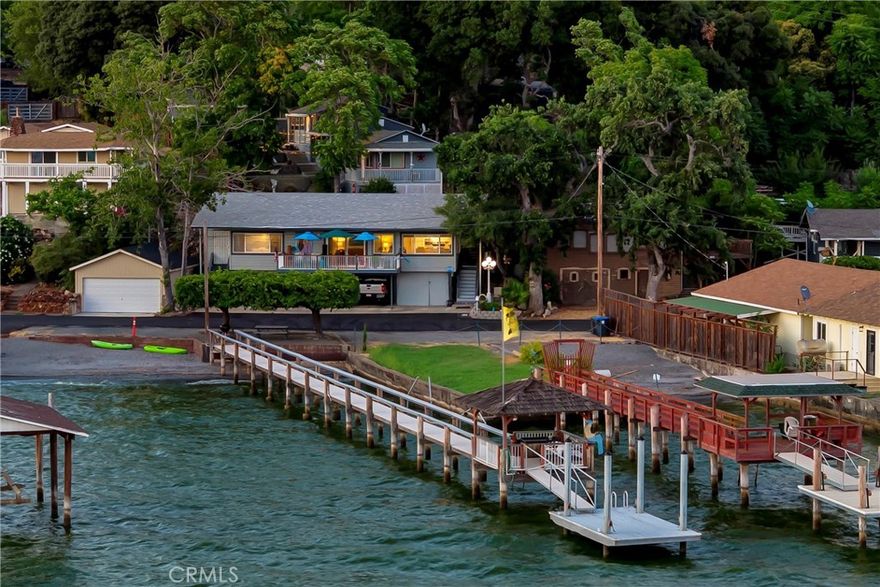 LAKEFRONT MULTI-FAMILY/INVESTMENT OPPORTUNITY! Welcome to a rare lakefront opportunity offering incredible versatility, charm, and income potential. Tucked in a desirable location on a quiet street with no through traffic, this peaceful retreat combines privacy with convenience—and yet is less than ten minutes from downtown shops and amenities.  Whether you’re dreaming of a private lakefront residence with income from rental cabins, a multi-family compound, or reviving a boutique resort, this property is ready to meet your vision. The main house is a 2BD/2BA with wood-beamed ceilings, rich natural light, and sweeping lake views from nearly an entire wall of windows. The updated kitchen features granite slab countertops and newer stainless steel appliances. Two single-car garage bays, two carports, and additional off-street parking ensure ample space for residents and guests alike.  Step outside to your own lakefront paradise. The approximately 180’ dock includes electricity, a covered area, and an adjustable swimming platform—perfect for sunny days on the water. Enjoy shaded lakeside picnics or relax on one of the many patios throughout the property. Included are five additional, turn-key cabins. Cabin #4 is a spacious 1BD/1BA (approx. 800 sq ft) with its own yard and private entrance. Cabins #1–3 are cozy studio units (approx. 280 sq ft each) complete with kitchenette, full bath, and private patios overlooking serene lake and mountain views. Cabin #5 is a smaller studio with a full bath—ideal for overflow guests or an office. A gated and covered RV space with electricity and water adds even more flexibility.  Originally part of a historic resort, the property is zoned Mixed Use – Commercial/Residential, providing endless possibilities: vacation rentals, long-term income, a private family compound, or a reimagined lakeside resort. With its tranquil setting, flexible zoning, and income-producing potential, this is a truly special opportunity on the lake!