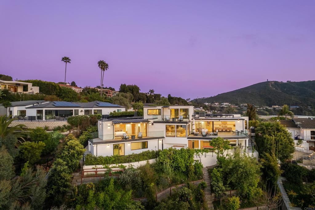 Perched above La Jolla Shores with sweeping coastal views, this 5BR/6BA sanctuary embodies relaxed California sophistication and seamless indoor-outdoor living. Nearly all spaces are on the main level—including the ocean-view primary suite—while a private upper-level guest wing gives visitors their own coastal retreat. Every bedroom has an en-suite bath, and multiple view decks offer endless moments to savor ocean breezes and fiery sunsets. Behind the gated entry, a serene courtyard with a pool and waterfall sets the tone for laid-back luxury. Inside, walls of glass and multiple La Cantina door systems open the main living areas completely to an expansive view patio—perfect for sunset dinners, weekend gatherings, or quiet mornings with coffee overlooking the shoreline. The chef’s kitchen with top-tier finishes flows into the dining and living spaces, where a striking glass-encased wine cellar becomes both a focal point and a conversation piece. On the lower level, a private wellness and leisure space awaits, complete with a gym space, sauna, jacuzzi, and a game room with pool table and TV—ideal for post-workout soaks, watching the big game, or unwinding with friends. A terraced hillside orchard of grapes, apples, citrus, and avocado trees brings a taste of California to your backyard. Renovated top to bottom in 2021, this turnkey home invites you to settle in and start living the La Jolla lifestyle—just minutes from beaches, dining, top schools, and freeway access.