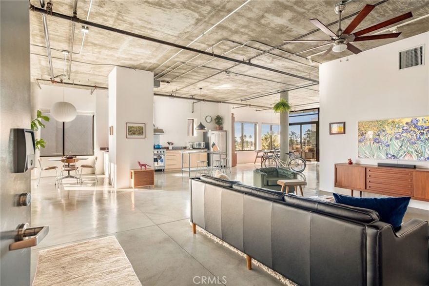 Perched on the top floor of the iconic Temple Lofts, this corner unit delivers the kind of design, light, and privacy that define true loft living. With nearly 1,800 square feet of open space, this one-bedroom home blends industrial architecture with modern upgrades in a way that feels both refined and effortlessly cool.

The northwest-facing orientation is a standout feature—floor-to-ceiling windows capture treetop views, wide-open sky, and colorful sunsets, filling the space with natural light all day long. Because of its corner location within the complex (facing 9th St), you get an uncommon sense of openness and privacy that’s rare in urban living. The private balcony extends your living space outdoors, making this home feel even larger and more connected to its surroundings.

Inside, polished concrete floors, soaring ceilings, exposed ductwork, and clean architectural lines set the tone. The chef’s kitchen features stainless steel appliances, granite counters, and a freestanding island perfect for cooking, hosting, or casual dining. The layout flows effortlessly between living, dining, working, and lounging moments—ideal for those who value both style and functionality.

A newly added full-height bedroom wall creates a fully enclosed primary suite while preserving the loft’s open flow, enhanced by a custom floor-to-ceiling primary closet and a beautifully designed entry closet, both by California Closets.

Originally built in 1927 as the Long Beach Masonic Temple, Temple Lofts is a celebrated example of adaptive reuse, where key architectural elements were thoughtfully preserved during its 2005 residential conversion. The lobby retains its original 1920s character, complete with historic tile, light fixtures, and period-appropriate detailing—setting a distinct tone the moment you enter. Modern conveniences complement the historic charm, including a fitness center, resident lounge, community deck with BBQs and a fire pit, secured guest parking, and on-site management. Unit 519 also includes a private storage cage (conveniently located at the entrance of the storage room) and two assigned side-by-side parking spaces for everyday ease.

Located in the heart of Long Beach, you’ll have easy access to the city’s best dining, coffee shops, farmers market, boutique fitness studios, entertainment, arts, and the waterfront—making this home an ideal landing spot for those who want space, style, and a connected urban lifestyle.