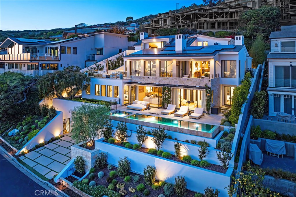 Perched in the exclusive gated enclave of Emerald Bay, this exceptional ocean-view estate captures breathtaking views of the pacific coastline. Rarely does a home of this caliber—where impeccable design meets superior craftsmanship—come to market. The property’s unique street-to-street lot, spanning approximately 9,460 square feet, ensures both privacy and accessibility in an unrivaled setting. Designed with an architectural vision to maximize views of Catalina Island, the coastline, and white-water waves from nearly every room, this residence epitomizes coastal luxury. The resort-like outdoor spaces invite seamless indoor-outdoor living, featuring an infinity-edge pool, spa, and expansive terraces perfect for entertaining in Laguna’s climate. The approximately 6,755-square-foot interior offers an effortless flow. The main level integrates the living room, family room, gourmet kitchen, and a private dining room, all framed by stunning ocean vistas. The lower level boasts four en-suite bedrooms, a second family room with a bar, and access to the breathtaking outdoor retreat. A private sanctuary awaits on the upper level, where the master suite opens onto an intimate terrace with commanding coastal views. Built with sustainability in mind, this environmentally conscious home incorporates state-of-the-art non-VOC materials, reclaimed woods, LED lighting, and a powerful 52-panel solar energy system. Additional highlights include a 4,500-gallon recirculating koi pond, a nearly 1,200-bottle wine cellar, Riviera Bronze doors and windows, gym, imported stone fireplaces, and a rare seven-car garage. Emerald Bay offers an unparalleled lifestyle with access to a private white-sand beach, six tennis courts, three sand volleyball courts, a community swimming pool complex, and parks. This is a rare opportunity to own a true masterpiece in one of Southern California’s most exclusive enclaves.