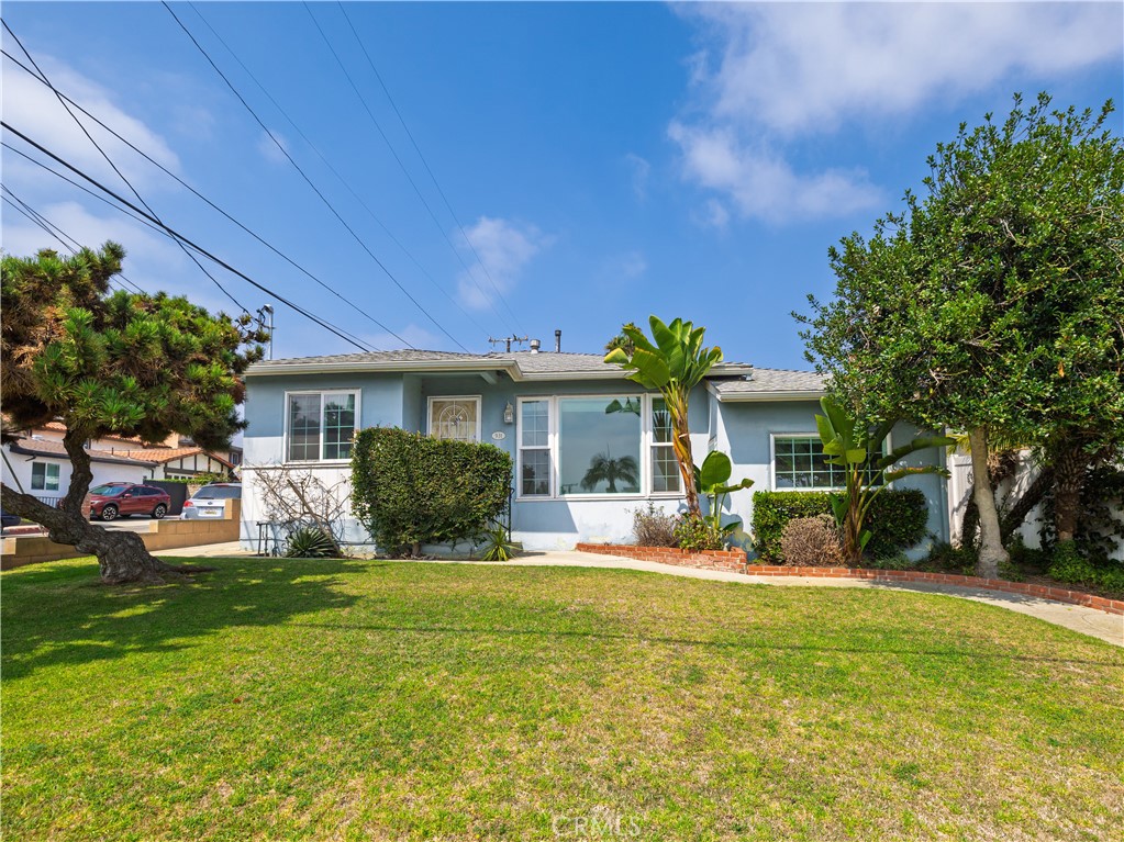 Welcome to 931 Hillcrest, a charming 3-bedroom, 2-bathroom home nestled in the heart of El Segundo. This thoughtfully designed residence offers a warm and functional layout, starting with an inviting living room that flows effortlessly into the dining area and kitchen. The kitchen includes a convenient laundry nook, pantry space, and access to the side yard—perfect for easy indoor-outdoor living.
Down the central hallway are two spacious bedrooms and a full shared bathroom, while the private primary suite features its own ensuite bath for added comfort. One of the secondary bedrooms opens directly to a lush backyard, creating a seamless connection to the outdoors. Adding even more flexibility is a separate den with its own entrance and full bathroom—ideal for a guest suite, home office, or creative studio.
A detached two-car garage is located at the rear of the property, framed by a mature lemon tree and a wide grassy area that’s perfect for play or entertaining. To the west, a gated 40-foot parking space provides dedicated room for a motorhome or boat. The home has also been upgraded with LAX sound insulation, enhancing peace and quiet throughout. This versatile and well-located property is a rare El Segundo find.