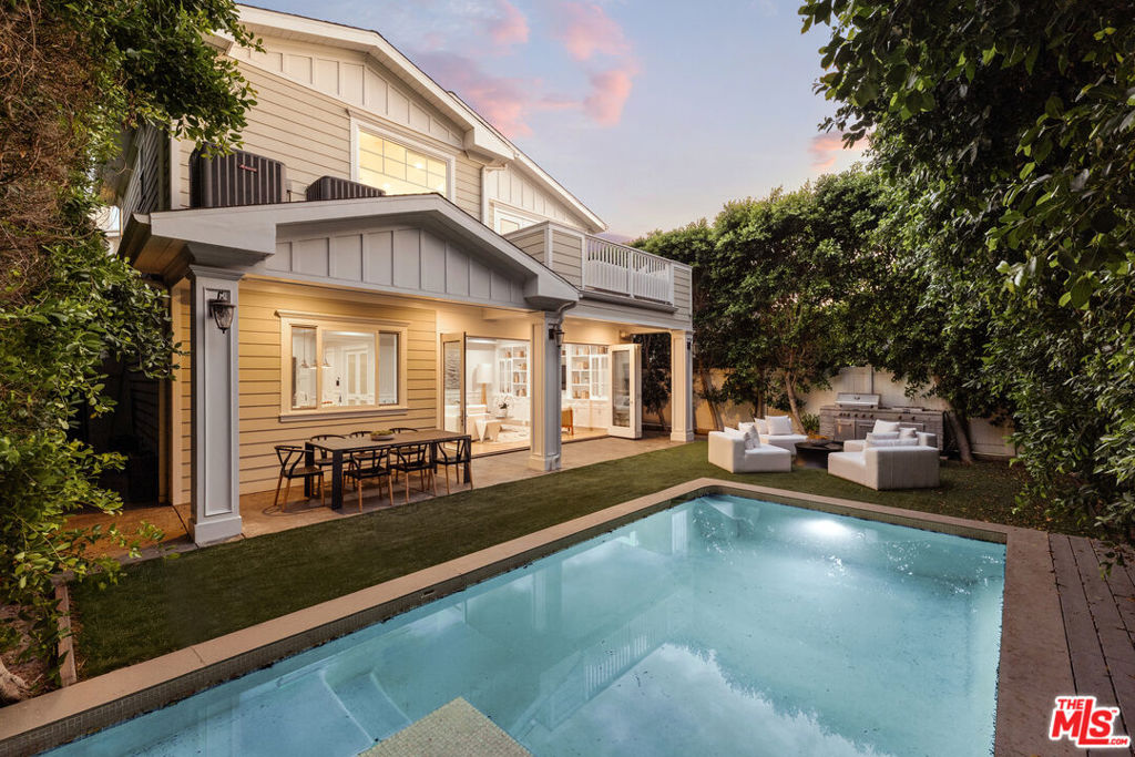 A newly reimagined Cape Cod retreat in the heart of Sherman Oaks, this 4-bedroom, 5-bathroom residence blends timeless design with modern sophistication across 3,815 square feet of living space. Soaring ceilings and expansive windows bathe the home in natural light, while refined details from coffered ceilings and wainscoting to white Carrera marble create an atmosphere of understated elegance.The formal living room, anchored by a stately fireplace, flows effortlessly into a dining room designed for intimate gatherings or grand entertaining. At the center of the home, the gourmet kitchen is a chef's dream, featuring custom cabinetry, a marble-topped island, Thermador appliances, and a walk-in pantry. A spacious family room with custom built-ins and folding glass doors opens to a covered patio, seamlessly merging indoor and outdoor living.Upstairs, the primary suite is a private sanctuary with cathedral ceilings, a fireplace lounge, and a private terrace overlooking lush treetops. The spa-inspired bath boasts dual vanities, a soaking tub, and an oversized shower with a built-in bench. A generous walk-in closet with custom built-ins completes this luxurious retreat. Three additional ensuite bedrooms and a versatile upstairs lounge offer comfort and flexibility for family or guests.Outdoors, the backyard unfolds into a private oasis with manicured lawns, a sparkling heated pool and spa with a soothing waterfall, and a covered terrace ideal for al fresco dining or relaxed evenings under the stars. Modern amenities including solar panels, a smart home system, surround sound, central vacuum, security cameras, and three fireplaces enhance both convenience and peace of mind.Located moments from the Sherman Oaks Galleria and Ventura Boulevard's dining and entertainment, this residence offers effortless luxury for those who seek "the good life."