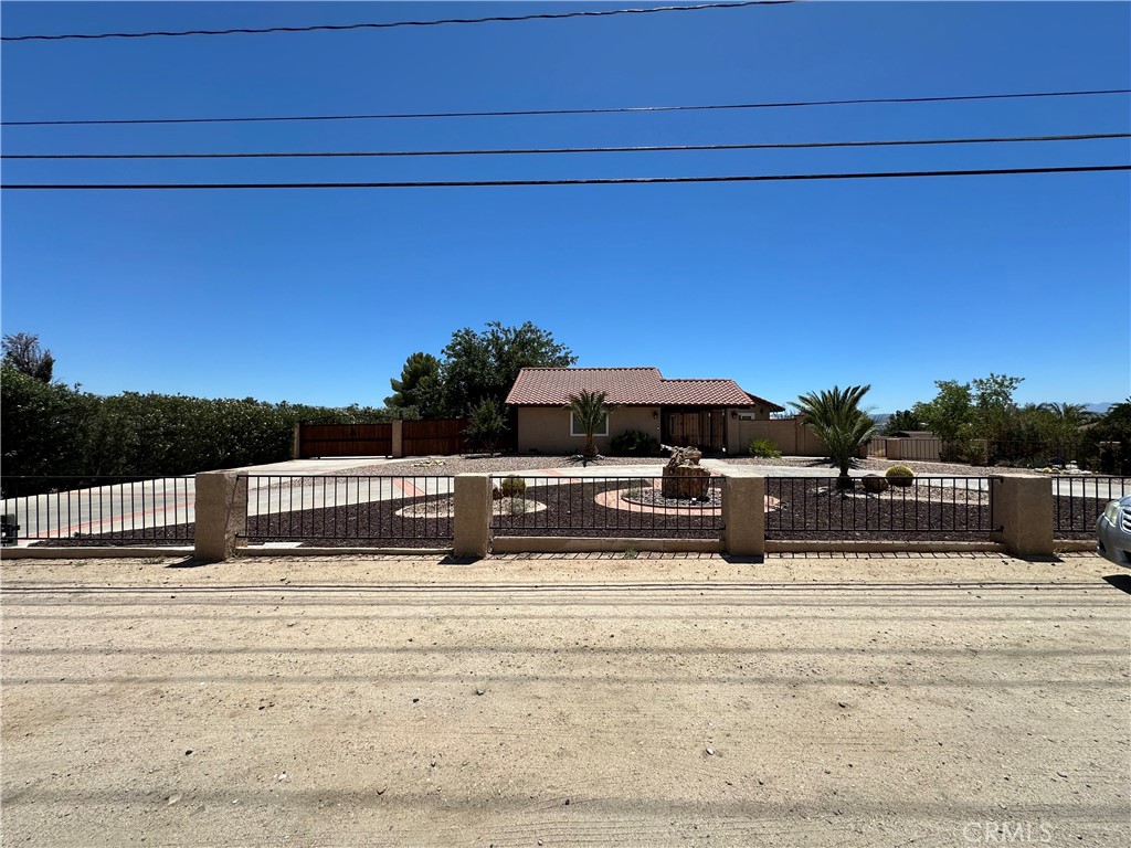 Welcome to this custom single-story home in the prestigious Desert Knolls neighborhood of Apple Valley. Set behind a private gated circular driveway, this 3-bed, 2.5-bath home offers 2,345 sq ft of well-designed space on over half an acre. Step into a serene courtyard with a waterfall feature and a grand front entry that opens to expansive living areas with a brick fireplace and natural light throughout. The kitchen is a chef’s dream with a center island, breakfast nook, and views of the southern mountains and city lights. The backyard is built for entertaining—featuring a covered patio, built-in BBQ, fire pit, and generous space for RVs, toys, or future enhancements. A spacious master suite opens directly to the courtyard, and additional highlights include an indoor laundry room, tile roof, security system, and an attached 3-car garage. Just minutes from shopping, golf, schools, and medical centers, with easy access to the 15 Freeway. No HOA, no Mello-Roos—just freedom, privacy, and views.