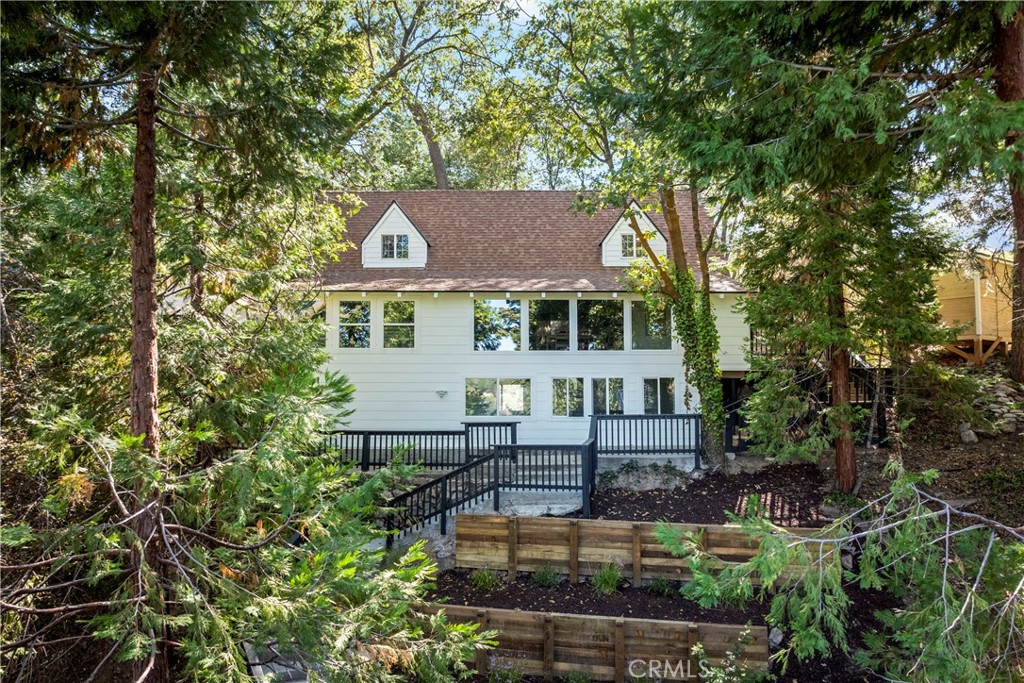 WOW, WOW, WOW!! Welcome to the Charlie Chaplin House Nestled in the Trees w/Incredible LAKE VIEWS! So Much Privacy & Just Across the Street From The Lake!! You are Literally Steps Away From Your INCLUDED 1/2 DOUBLE DOCK!! Run Down and Take a Boat Ride, Go for a Run Around the Lake or How About a Refreshing Swim? And Wait Until You See Inside!! Just Remodeled From Head to Toe & Professionally Designed w/Premium Finishes Throughout!! Four Bedrooms, 3 Baths and an Incredible Outdoor Entertainment Deck Area with a Sheek Bungalow Perfect for Gathering, Games and Refreshments! ALL NEW Modern Rustic Kitchen with Tumbled Limestone Backsplash, Beautiful Wood Cabinetry and Brazilian Honed Dolomite Countertops. Open Living Areas with 2-Story Ceilings and Island Breakfast Bar to Gather & Enjoy Meals. There is an En-Suite Bedroom on the Main Level and a Separate Bathroom for Guests. Downstairs is an Elegant and Private Master Suite to Enjoy, All to Yourselves! Oversized Shower and Lakeviews from the Bedroom Make this Oh Sooo Relaxing! Up the Private Starway Above the Kitchen is the Cutest Bunk Room for the Kiddos! They Will LOVE it!! And the Private Stairway Above the Living Room Leads to the 4th Bedroom, Currently Being Used as an Office. Offered Turnkey with Everything As You See it Today!! It's Difficult to Get BOTH a Lake View AND Be Close to the Lake Here in Gorgeous Lake Arrowhead!! This One Has BOTH!!! Come & Enjoy All that Lake Arrowhead Has to Offer with this Incredible Full Lake Package - Coolest Lake View House with a Private Dock Just Below! Just Bring Your Toothbrush!! Everything is Ready and Waiting for You!