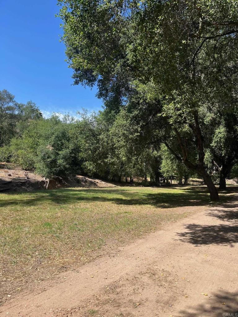 A once-in-a-lifetime opportunity to own a truly special property—on the market for the very first time. A gently winding, tree-lined driveway runs alongside a seasonal creek bed, creating a peaceful natural backdrop and unmatched sense of serenity. Tucked away at the end of a secluded oak-lined lane, this 3.41-acre sanctuary offers a rare blend of privacy, nature, and timeless charm. Lovingly built and meticulously maintained by the original owners, this single-level home features 3 bedrooms plus an office, 3 full baths, formal living and dining rooms, and a cozy family room with expansive windows framing tranquil views of the surrounding trees and landscape. The inviting kitchen includes a center island, built-in desk area, and opens to a peaceful patio—perfect for sipping your morning coffee while taking in the sights and sounds of nature. A large freestanding workshop with windows offers incredible potential for creative or practical use. An RV pad is already in place, and there’s ample space for an ADU, horses, vineyard, or any dream you’ve been waiting to bring to life. Properties like this are rarely available—peaceful, soulful, and full of promise. Don’t miss your chance to own this one-of-a-kind nature lover’s haven. Just minutes from the heart of The City in the Country and within the award-winning Poway Unified School District.