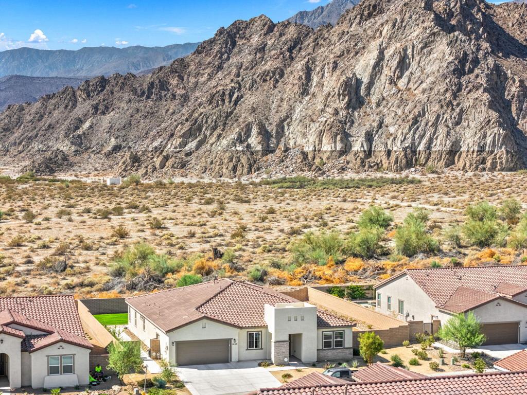 La Quinta at its finest!! Don't miss on this stunning south facing residence in the heart of the Cantera at Coral Mountain community. A professionally landscaped backyard affords the feeling of intimacy to the mountains. A custom built-in barbeque ensures low-desert sunsets are even more pleasurable. This two-year-old, professional owned residence exemplifies pride of ownership. A beautiful home featuring 3,006 square fee t of warm luxurious living space. The bright and open kitchen features an expansive island, custom buffet comprised of floating cabinets and shelving, professional sized refrigerator and an entertainment wall along with a custom speaker system completes the open living space. An extended driveway, additional storage and workout area compliment the garage space.