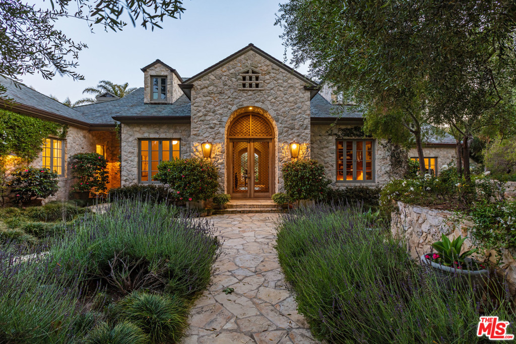 Completely re-envisioned, this chateau-like oasis rests on the most exclusive street in Point Dume. Custom draperies, architectural archways, and white oak cabinetry are just a taste of the meticulously curated elements in this one-of-a-kind residence. Whether it's the reclaimed limestone kitchen flooring and powder room sinks, or the marble countertops beside broken-in wood, this modern, comfortable sanctuary has a been-there-forever feel. On 1.48 acres and nestled among graceful palm trees, the main house holds four bedrooms and six bathrooms, a full wine room, and a wood-paneled library, a formal dining room, and an elegant living room, each with custom fireplaces. The primary suite boasts a contemporary sitting room, fireplace, and dual bath and closets. Outside, enjoy the guesthouse, pool, spa, kitchen situated between orchards and vegetable gardens, and Riviera 1 beach access. The French Riviera is closer than ever thought possible.