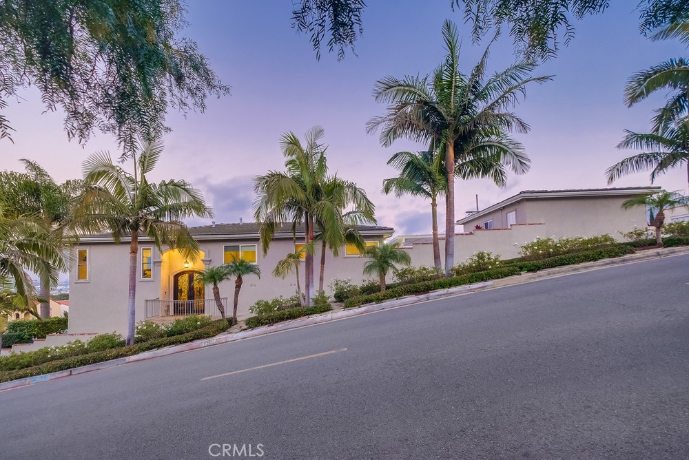 Perched high on a coveted corner lot in San Pedro, this exceptional residence offers a rare blend of luxury, functionality, and sweeping panoramic views that span from the glittering skyline of downtown Los Angeles to the coastal beauty of Dana Point. From majestic mountain ranges and harbor activity to the endless Pacific Ocean, the vistas are truly unmatched. Thoughtfully reimagined with elegance and comfort in mind, the home welcomes you through a custom double iron entry into an expansive, light-filled living and dining area framed by oversized picture windows that capture the ever-changing scenery. Start your mornings on the view balcony, where sunrises over the Saddleback Mountains set the tone for the day. At the heart of the home lies a chef-caliber kitchen, complete with bespoke cabinetry, granite countertops, a natural stone backsplash, dual walk-in pantries, and premium stainless steel appliances. The upper level also features a tranquil primary suite with a cozy sitting area, cedar-lined walk-in closet, and a spa-inspired bath with heated floors and a luxurious walk-in shower. A beautifully appointed guest bedroom, upgraded bathroom, and a large laundry room with built-in cabinetry and folding counters complete this level. A travertine staircase with a custom iron handrail leads to the lower level, where you'll find a generous family room with a fireplace, a spacious bedroom, a sleekly remodeled ¾ bath, and a versatile flex room with a wet bar—ideal for a home office, gym, wine cellar, or potential kitchenette to create a private guest suite or multi-generational living space. Two oversized walk-in storage rooms provide abundant storage options. Outside, the rear grounds were designed with entertaining in mind: a large patio with pergola, built-in BBQ, composite deck, raised planters, and space for a vegetable garden—all with views of the harbor and ocean. Completing the property is a detached three-car garage with finished interior and custom cabinetry. With plumbing and electrical already in place, the garage offers excellent potential for conversion to an accessory dwelling unit (ADU), providing endless flexibility for guest quarters, rental income, or studio space. This rare offering exemplifies coastal California living at its finest—luxurious, versatile, and truly unforgettable.
