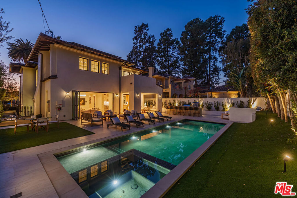 Set in the esteemed North of Montana neighborhood of Santa Monica on a nearly 9,000 SF oversized lot, this custom-built new construction blends quality craftsmanship with exceptional amenities and scale. Spanning 6,860 SF with 4 bedrooms + office and 7 bathrooms across three levels, this home delivers seamless indoor-outdoor flow and expansive spaces built for elevated living and entertaining. The main level offers soaring ceilings and expansive living spaces, including a formal living room, dining room, dedicated office, and an open-concept kitchen outfitted with bespoke cabinetry, butler's pantry, and Miele, Sub-Zero, and Wolf appliances. Fleetwood doors connect the interiors to a private backyard retreat featuring a heated pool and spa with automatic cover, a built-in BBQ and pizza oven, and multiple zones for dining and lounging. Upstairs, wide-plank oak flooring leads to three generously sized en-suite bedrooms, including a reimagined primary suite with a newly expanded oversized walk-in closet. The amenity-rich basement level includes a lounge and bar, movie theater, wine cellar, guest suite, and full spa with both wet and dry saunas. Mature ficus trees line the front of the home for added privacy and additional highlights include solar panels, multi-zone climate control, Control4 smart home system, and a three-car garage. Located just moments from Montana Avenue, San Vicente, and Brentwood Country Club, this home offers a rare opportunity to enjoy scale, privacy, and convenience in one of the Westside's most sought-after neighborhoods.