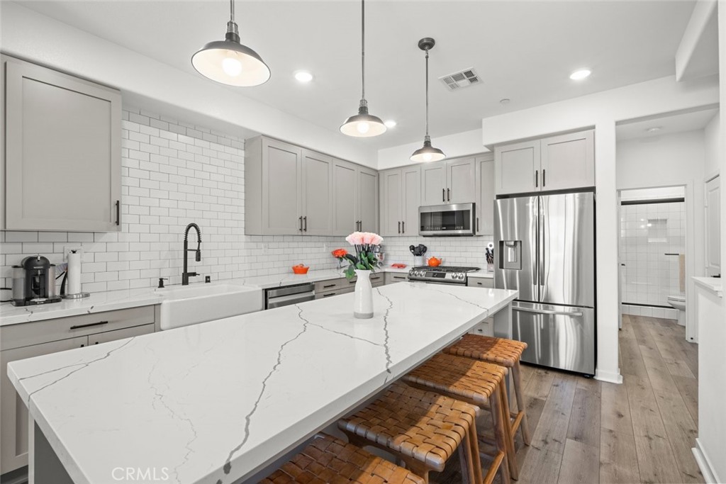 Welcome to this stunning townhome, on a great location within the delightful Flora Walk community. Built in 2021, this residence has been meticulously maintained and upgraded. The home offers 3 bedrooms, 3 bathrooms, and 1,430 sq ft of living space. The home boasts of natural light, Luxury Plank Flooring throughout the home, kitchen, living room, bedrooms, and stairs. This unit has soaring 9-foot ceilings across three levels with recessed lighting. Enjoy abundant natural light through numerous dual-paned windows. The expansive kitchen features spacious cabinetry with soft-close doors and drawers, beautiful countertops, a full backsplash, and a beautiful center island with White Quartz Countertops. The home is also equipped with pendant lights, a large farmhouse white sink with lovely faucet, and high-end stainless-steel appliances, including a 6-burner range, a pro-style exhaust hood, a dishwasher, and a microwave. The bright and open living room features vaulted ceilings and recessed lighting, with a spacious dining area complemented by lots of natural light. On the main floor, you’ll find the living room, dining area, kitchen, and a convenient bathroom. Convenient Bedroom on the main floor. Two bedrooms are located upstairs, ensuring close proximity for family living. The primary bedroom is generously sized, offering a private bathroom suite and a spacious walk-in closet. The primary bath includes a separate shower, dual sinks, and a separate commode room. Additional amenities include central heating and air conditioning for year-round comfort, a laundry area with ample storage & countertop space, a convenient attached 2-car tandem garage with an EV charging outlet, water softener, an auto roll-up door. The garage also features a Tankless Water Heater Filter System & direct access to the home. There is ample guest and street parking available. Walking distance to the community area, which includes a patio with seating and a barbecue, community firepit is ideal for relaxing and entertaining. Pet Friendly Community. Flora Walk offers easy access to the 405 and 110 freeways. HOA dues are just $284 per month. Act quickly—this home won’t be available for long!