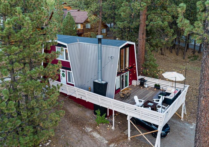 FULLY FURNISHED! Just off Big Bear Blvd. on a 0.75-acre lot you will find  Lucky Bear Cabin a charming and beautifully updated 2-bed, 1-bath gambrel-style cabin with 1,095 square feet of living space and an expansive raised deck. This mountain retreat is move-in ready, fully furnished, loaded with thoughtful upgrades.  Over the past 4.5 years, the current owner has made significant improvements, including: a new 50-year life metal roof, Upgraded/Replaced electrical panel and several dedicated outlets, string lights on a dimmer, Dual-pane windows and replaced patio sliders, Replaced water heater, wall heater, and thermostat, Fully remodeled kitchen with stainless steel appliances, a black composite granite sink, and modern finishes Drywall and upgraded insulation for enhanced energy efficiency, Partially updated bathroom, Luxury vinyl plank flooring downstairs, 18,000 BTU mini-split AC and heat unit installed in the loft, Radiator in downstairs bedroom,  Installed electric & chandelier in the main living space, Asphalt Driveway was replaced, Installed easy to access water shutoff (close to entryway- by licensed plumber) Blink Security Camera System, Television in Livingroom.  Step outside to enjoy a freshly refinished deck treated with Cabo Deck Correct and replaced deck railing, a newly poured walkway and concrete slab leads you to the newly installed 4 person-spa. Deck features a BBQ, Firepit, cooling box, storage and a seating group. The property also includes a lockable storage area under the house, ideal for tools, gear, or seasonal supplies.  This fully furnished cabin is stocked and ready for enjoyment with lots of extra linens, towels, kitchen supplies and even Christmas decor. Included are a foosball table, game closet, projector and screen, and outdoor games for all-season fun and relaxation. Fire place in living room for those cold nights featuring a stunning antique stained glass cover.    Whether you’re looking for your forever home, serene second home or a high-potential short-term rental, Lucky Bear Cabin is a rare find that combines rustic charm with modern comfort.  Schedule your tour today and experience the magic of Lucky Bear Cabin for yourself.