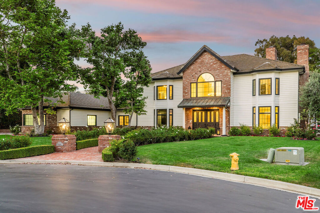 Welcome to 11060 Hildreth Court, A Timeless Masterpiece in Camelot Estates. Tucked away at the end of a quiet cul-de-sac in Santa Rosa Valley's prestigious Camelot Estates, this custom-built Modern Colonial home offers nearly 5,700 sq ft of refined living space on a flat 1.12-acre lot. Located within one of Ventura County's most exclusive gated enclaves, this estate captures the essence of privacy, prestige, and peaceful living. From the moment you arrive, a grand tree-lined approach and manicured rose gardens lead to an inviting entry framed by sweeping views of Montclef Ridge. Inside, antique beveled-glass double doors open to a formal foyer with soaring ceilings, gleaming refinished solid oak floors, and elegant wainscoting, crown molding, and wide hotel-style hallways. The formal living room stuns with herringbone floors, custom drapes, and a centerpiece fireplace, while the family room features whitewashed brick, coffered ceilings, and twin French doors that open to the expansive backyard, creating seamless indoor-outdoor flow. At the heart of the home is a chef's dream kitchen with custom cabinetry, quartz countertops, white-washed Saltillo tile, and professional-grade Thermador appliances. A massive center island with dramatic pendant lighting anchors the space. Adjacent is a built-in breakfast nook and a charming butler's door that leads to the elegant formal dining room complete with designer wallpaper, wainscoting, chandelier, and French doors opening to the yard. A remodeled powder room dazzles nearby, while a spacious guest suite with its own outdoor entrance and en-suite Italian-tiled bath provides privacy for multigenerational living or staff quarters. Two dedicated offices enhance remote productivity: a gentlemen's cigar library with fireplace, floor-to-ceiling shelving, a secret room, and bay windows, and a second space ideal as a craft room or homework zone with built-ins and natural light. Upstairs, the primary suite is a private sanctuary with vaulted ceilings, wainscoting, a double-sided fireplace, and French doors to a large balcony with unobstructed mountain views. The spa-inspired en-suite features dual vanities, a boudoir dressing area, double walk-in closets, a bay-set soaking tub, Carrara-style tile, a Jason Wu walk-around shower, heated towel racks, and its own fireplace. Three additional upstairs bedrooms each include en-suite designer baths, plush Berber carpets, and custom built-ins. Even the laundry room is upscale with butcher block counters, ample cabinetry, and bohemian tile flooring. Car enthusiasts and hobbyists will love the 4-car attached garage and separate RV garage with epoxy flooring and an industrial fan, ideal for a gym, workshop, or storage. Step into your private backyard oasis, where entertaining reaches new heights. The resort-style grounds include a luxurious pool and spa, a gravel firepit lounge, multiple seating and dining areas, built-in BBQ, fruit trees, rose gardens, wide green lawns, and 15-foot privacy hedges. Formerly used for weddings, this level, landscaped yard evokes the charm of a private park. Other features include five fireplaces, a billiard/game room with TVs, a dartboard, wet bar, and a walk-in wine closet. Additional upgrades include a solar lease system, dual-zone HVAC, remodeled 3,500-gallon septic tank, LED lighting, and access to affordable agricultural water. Living in Camelot Estates means more than just owning a home. With just 59 custom residences, this exclusive gated community offers private bridle trails, serene open space, and proximity to top-rated schools, golf courses, Camarillo Outlets, Reagan Library, Underwood Farms, and scenic trails. Here, elegance, comfort, and community meet in perfect harmony. Welcome to Camelot where dreams are built to last.