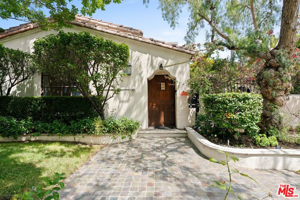 Timeless Spanish Charm Meets Modern Luxury in the Heart of Beverly Hills. Behind a gated entry, a central courtyard sets the tone for this elegant single-story residence with 3 bedrooms and 2.5 baths in the main home plus a detached 1-bedroom, 1-bath guest house adds versatility for visitors or a home office. The spacious living room features a large fireplace and French doors that open to the sunlit courtyard, creating seamless indoor-outdoor living. A formal dining room leads to the chef's kitchen, appointed with Viking appliances, custom mahogany cabinetry, a breakfast nook, and abundant storage. The primary suite offers French doors to the backyard and a beautiful bathroom with double vanities, designer tile, and a claw-foot soaking tub. Two additional bedrooms are thoughtfully appointed, one with its own en suite bath and the other conveniently served by a nearby half bath. Additional highlights include upgraded plumbing, hardwood floors, a security system, and central air conditioning. The lush, private grounds are designed for entertaining, featuring a sparkling pool with spa jets and waterfall, an outdoor fireplace, built-in Viking BBQ, and limestone patio. Located just moments from world-class dining, shopping, and entertainment, this property combines timeless architecture with resort-style amenities in one of Beverly Hills' most coveted neighborhoods.