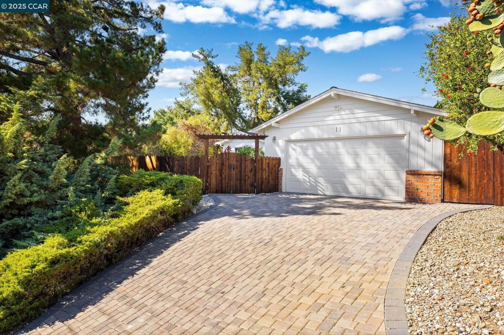 Tucked on a quiet court in Pleasant Hill, this remodeled single-story home combines modern updates with inviting indoor-outdoor living. Inside, the spacious living & dining combo centers on a brick fireplace with built-ins and direct access to the yard. The updated kitchen features granite counters, a gas range, pantry storage, and bar seating that opens to a welcoming breakfast nook, ideal for everyday meals. A wall of custom cabinetry with glass-front uppers and wine storage adds both elegance and utility. Three bedrooms provide comfortable retreats, each with hardwood floors. The primary suite features a private bath with dual sinks and a stall shower, while the hall bath also offers a walk-in shower and ample vanity space. Outdoors, enjoy a variety of spaces for relaxation and entertaining. A private front courtyard with paver hardscape and built-in firepit sets the tone for gatherings. The backyard extends the lifestyle with a covered patio, pergola seating area, and a custom putting green surrounded by mature landscaping. Set on a corner lot with a paver driveway, this home blends privacy and convenience. Its location offers easy access to neighborhood parks, top-rated Pleasant Hill schools, BART, and major commuter routes.