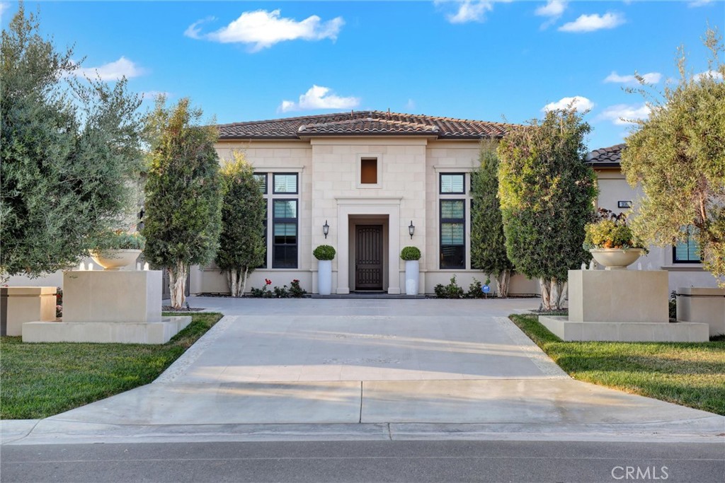 Rare SINGLE-STORY “ESTANCIA” estate with soaring ceilings (16 feet in Grand Room area), luxury finishes, and exceptional indoor-outdoor flow. Step into refined elegance with this stunning single-story estate offering approximately 5,143 square feet of thoughtfully designed living space with REAL FRENCH OAK WOOD flooring through-out. From the moment you enter you’ll be greeted by soaring ceilings that create the feeling of a grand two-story space—without a single stair in sight. At the heart of the home, a modern, dramatic rotunda-style entry sets the tone, leading you into two private wings. One wing features 2 spacious en-suite bedrooms, each with their own bathroom (and extra bonus room/laundry rooms with access to a mudroom and garage entry—perfect for multigenerational living). The opposite wing houses the luxurious primary suite with 13 foot high ceilings and its own private retreat: a SPA-INSPIRED BATHROOM with dual vanities, soaking tub, separate shower, and an expansive walk-in closet. A 4th bedroom with own en-suite bath completes this wing, ideal as a guest suite or flex space which also has access to a mudroom and garage entry. The main living area is a showstopper—an OPEN-CONCEPT GREAT ROOM combining the kitchen, living room (with 60" linear natural gas fire place), dining, and outdoor patio areas under breathtakingly high ceilings and ABUNDANT NATURAL LIGHT. The CHEF’S KITCHEN is fully upgraded with premium appliances, an OVERSIZED QUARTZ WATERFALL ISLAND with a 24" wine cellar, a large breakfast nook, and matte European-style smooth wall finishes throughout. Designed for seamless INDOOR-OUTDOOR LIVING, the north wall of the primary suite and the main living area open completely with BIFOLD GLASS DOORS, creating a stunning transition to the expansive backyard. The outdoor space is equally impressive featuring a covered patio, BUILT-IN BBQ with sink and single gas burner, a serene waterfall fountain, RAISED GARDEN BEDS for homegrown produce, lush landscaping with fragrant roses, and two front-yard fountains. Other standout features include: 2 A/C units, a TANKLESS water heater, WATER SOFTENER, SECURITY system, and SOLAR panels. This layout maximizes privacy and flow. Homes like this are rarely available—single-story, incredibly spacious, custom-quality construction, and designed for both luxurious comfort and effortless entertaining. A true one-of-a-kind property.