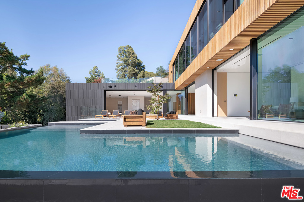 A stunning modern architectural gem with a prestigious 90210 address in the serene hilltops of Beverly Hills and a PRICE REDUCTION of $1,755,000 less than the original price makes this home that much more attractive. Nestled off Hazen Drive in Beverly Hills, California, on a private quiet cul-de-sac, you will discover a modernist Tag Front gem, with walls of glass that open to abundant trees, absolute privacy, and serene green hilltop views. This home has three levels of 8,802 square feet of seamlessly designed interior living space with immense scale and openness that leans into an effortless indoor-outdoor lifestyle. Expansive outdoor balconies, terraces and an inviting infinity pool deck with a rooftop outdoor kitchen offers boundless entertainment opportunities. The exterior is designed with cool stone and metal hues complementing the rich woods and living wall found around the property. Luxurious textures and intentional materials found within the interior and exterior were specifically chosen for quality, prestige and beautiful design. Stone and wood wall treatments and white oak hardwood floors lend a rich, warm feeling to the home. 9330 Hazen Drive is beautifully built with 6 bedroom suites, 10 bathrooms, a complete family room, cooks kitchen, pool lounge, a sleek elevator, a separate loft guest house and a Tag Front designed interior and exterior. The home features an outdoor entertainment area and sophisticated smart home system. An infinity pool, Baja deck and infinity edge spa look out onto the sweeping views from the city to the ocean. The home is perfectly crafted for enjoying a luxe lifestyle, close to the heart of Beverly Hills, yet tucked away into the hills offering complete tranquility, privacy, serenity and a true escape. Total home purchase price value is $13,500,000