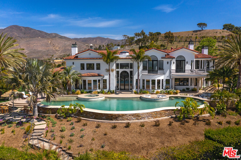Magnificent resort-style equestrian compound, approx. 3 acres, exceedingly private, with ocean views. Grand scale, light-filled residence sited on a knoll at the end of a long, gated drive.Chandelier foyer steps down to dining room and majestic living room with coffered ceilings,fireplace and ocean views. Kitchen with island and breakfast area blends classic details with high quality appliances. Adjacent dining cove opens to family room with wet bar. Hallway leads toen-suite bedroom, laundry room, large deck and outdoor living/dining area over four-car garage.Main floor has three more en-suite bedrooms, plus large office, and lower-levelbonus/media/game room. Upper level has fitness room and two more en-suite bedrooms,including ocean-view owners suite with dual closets, luxe bath, fireplace seating, and large view balcony. Grounds feature numerous areas to dine, relax, play, and entertain. Ocean-view backyard has huge Pebble Tec infinity pool and spa with swim-up bar, fire pit seating, outdoor kitchen and barbecue, tiki hut, batting cage, drip-irrigated olive grove. Equestrian facilities include barn, tack rooms, workshop, laundry, bathroom, corral, riding ring, hot walker. Property has four water tanks, sprinklers in house and barn, security, guest parking. A compound of rare quality and beauty, designed for a lifestyle of exquisite ease.