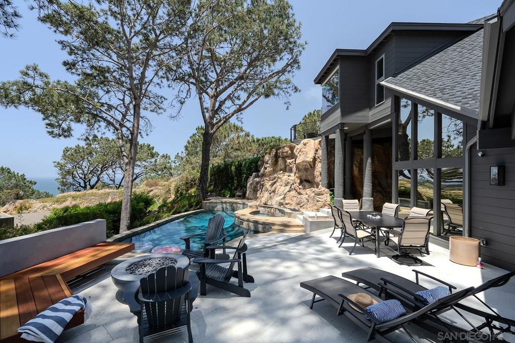 Enjoy the one-of-a-kind ocean and sunset views from this coastal retreat set among the bluffs and trees of Del Mar. This unparalleled 14,400 sf property will have you and your guests awe-inspired by the natural beauty of this location. Lodged into the sandstone bluffs and nestled below the towering Torrey Pines, this home has been completely reimagined to embrace the sweeping ocean views from every room in the house. Designed with modern sensibilities and indoor-outdoor living in mind, the home features an open floor plan with large skylights, flooding the interior living space with natural light. The multi-slide pocket door disappears to seamlessly open the interior to the west facing deck and salt water pool. Spend time with your family and friends sitting by the new fire pit or soaking in the spa while the rock waterfall runs down and the sun sets in the distance. Finish the evening in the courtyard tucked into the bluff and enjoy the warmth of the gas fireplace. Wake up every morning to the sound of crashing waves and white water views from the privacy of the primary suite perched atop the bluff. Take your own private elevator to the primary suite and relax in the spa-like bathroom with a soaking tub and large shower. Down the hall is a large walk-in closet with a coffee bar. Sip an early morning espresso from the primary suite deck with its own gas fire pit. This peaceful, private retreat is truly special.