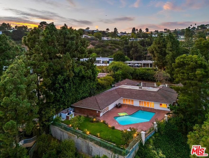 This rare sunlit 1962 Trousdale Estates custom-built one-level and one-owner gated Hawaiian Modern estate is replete with extensive original terrazzo flooring, lava rock, high ceilings, curvature, and southern/southeastern/southwestern vistas. Semi-circular retro entry foyer leads to large living and family rooms opening to the substantial grounds with patios, lawns, pool, spa, BBQ center, and views. Family room features a fabulous step-down "martini" bar. Super cool expansive kitchen thematically updated over the years. Generous primary suite opens to the grounds with closets galore, vanity area, and a great bath with sunken terrazzo tub. In addition to the primary, there are 3 other bedroom suites on the western side of the home along with several redone bathrooms. Ample off-street parking with large gated motorcourt and 3-car carport. Sited with authentic curb appeal on a generous street-to-street corner lot and exhibiting a tremendous flat pad, the potential is endless for 500 Leslie Ln to become a gem in this prestigious mid-Trousdale coveted and exclusive 6-home cul-de-sac.