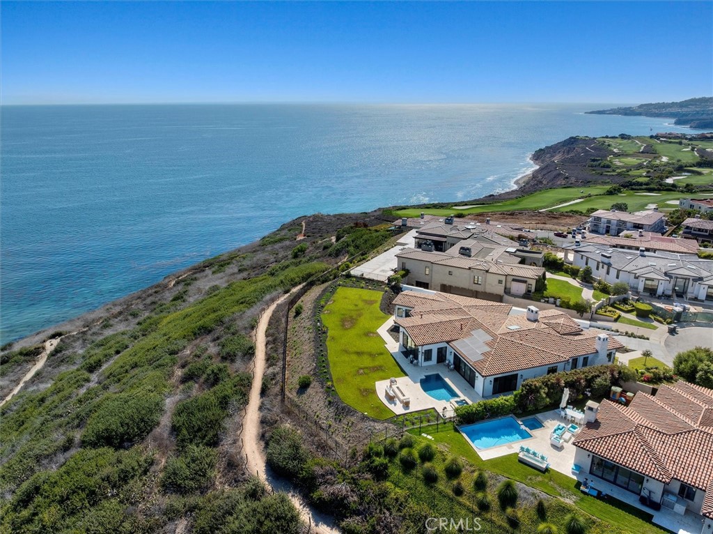 A Signature Coastal Estate in Rancho Palos Verdes’ Most Coveted Enclave
Modern Grandeur with Iconic Pacific Ocean Views
Commandingly sited on an elevated lot with unobstructed views of the Pacific and Catalina Island, this newly built architectural estate is a rare offering in the prestigious Estates at Trump National. A testament to minimalist luxury and refined coastal design, this contemporary masterpiece spans approximately 9,371 square feet of airy, light-filled interiors — a home where clean lines meet grand-scale sophistication.
Crafted with precision and restraint, the residence is defined by its voluminous spaces, gallery-like flow, and meticulous attention to modern detail. Step inside to a soaring foyer drenched in natural light, where refined stone floors and sleek finishes set the tone for the understated elegance carried throughout the home.
Formal living and dining rooms are ideal for elegant entertaining, while the chef’s kitchen — anchored by a sculptural oversized island — features top-tier appliances, custom cabinetry, and seamless integration into the casual living space. Designed for those who entertain with intention, the layout balances openness and intimacy with effortless grace.
The home offers six expansive en-suite bedrooms and eight baths, including a serene main-level primary suite with sweeping views and private access to the pool terrace. A spa-inspired bathroom and walk-in closets complete the retreat. On the lower level, a generous bonus room awaits transformation into a home theater, screening lounge, or game suite, while a flex space offers potential for a private gym, wellness sanctuary, or executive office.
An in-home elevator provides discreet convenience, supporting multigenerational comfort and long-term ease.
Outside, resort-style grounds are framed by the Pacific horizon. A shimmering pool, spa, and built-in firepit create a scene as visually stunning as it is functional — the ultimate canvas for golden-hour entertaining or quiet coastal contemplation.
With a 5–6 car garage and long driveway accommodating additional 5-6 vehicles, the estate pairs luxury with lifestyle.
Moments from world-class golf at Trump National, coastal trails, and some of the West Coast’s most cinematic ocean vistas, this home is not merely a residence — it’s a destination.