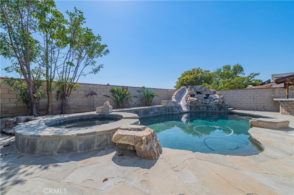 Upgraded pool home on a spacious 7,280 sqft lot! This 4-bedroom, 2-bath residence is freshly painted throughout, with brand new roof, new bedroom flooring, new ceiling fans in every bedroom, brand new kitchen countertops, and new toilets in both bathrooms. The very open floor plan connects seamlessly to the backyard, with sliding doors from the living room and French doors off the dining area. Interior highlights include beautiful wood-style flooring, brick accents, crown molding, baseboards, and wainscoting, plus a custom brick fireplace in the dining area. Bedrooms are spacious, with one double-door bedroom ideal as an office, and the primary suite offers a private bath with a deep soaking tub. The backyard is designed for entertaining, featuring a dark-bottom pool with waterfall, slide, and swim-up stools, a large patio, built-in BBQ, covered bar area, custom outdoor fireplace, and multiple seating nooks. Conveniently located within walking distance to El Toro High School and close to shopping centers, restaurants, schools, library, and freeway access—only about 10 minutes to Irvine Spectrum.