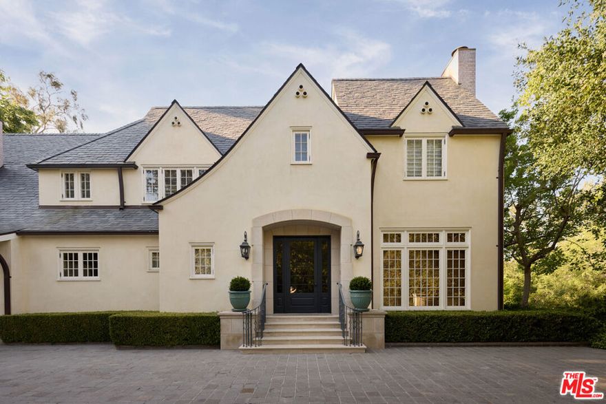 Nestled south of Sunset Boulevard, just steps from the renowned Holmby Park, this grand English Country Estate epitomizes timeless elegance, masterful craftsmanship, and modern luxury. Situated on an expansive corner lot, this architectural masterpiece was taken down to the studs and meticulously rebuilt by renowned architect Richard Manion and master builder Richard Holz, incorporating state-of-the-art systems throughout.Spanning over 10,000 sq. ft., this gated estate offers the utmost privacy and an effortless blend of classic sophistication and contemporary comfort. The formal living room is a showstopper, featuring exquisite French doors on both sides that create a seamless indoor-outdoor flow, ideal for grand entertaining. At its heart is a striking Chesney's English marble fireplace, adorned with rare Brazilian blue Sodalite. Adjacent, the mahogany-paneled library exudes warmth, featuring another Chesney's London marble fireplace and bespoke cabinetry, while the formal dining room is designed for both elegance and functionality, offering hidden European-hinged storage.The gourmet kitchen is a true chef's haven, bathed in natural light from overhead skylights and anchored by a custom steel and brass range hood painstakingly handcrafted over a year. It boasts professional-grade appliances, a butler's pantry, and a sunlit breakfast nook. The inviting family room features coffered ceilings, a built-in bar, blackout curtains, and surround sound, creating the ultimate retreat.Outside, the estate's lushly landscaped grounds are designed for serenity and grand-scale entertaining. Meandering pathways lead through a botanical garden, punctuated by three fountains, a tranquil pond, and vibrant flora. The expansive pool deck now features a saltwater pool, fire pit, lounge area, and a covered pergola, in addition to a spa, an outdoor dining pergola with seating for 45+ guests, and stone bench-lined patios, all designed for seamless al fresco gatherings. Additional outdoor amenities include a half basketball court, parking for 10 cars, and a separate dog run.This remarkable residence offers seven bedrooms, each with an en-suite bath featuring exquisite materials such as all-marble slabs, onyx, quartz, and mosaic tile flooring sourced from Studium NY. The primary suite is a true sanctuary, complete with a private terrace, exercise and reading nook, fireplace, dual spa-like marble baths with heated floors and a steam shower, custom walk-in closets, and multiple seating areas.Equipped with cutting-edge smart home technology, the estate features a state-of-the-art security system, smart Lutron lighting, a 17-unit HVAC system with 21 temperature zones, reverse osmosis water filtration, and an efficient self-testing generator. Additional luxuries include an elevator, gym, wine cellar, two home offices, cedar storage, a gift wrap room, a mechanical basement, and a three-car garage with separate staff access.Every detail of this extraordinary home has been thoughtfully curated to offer an unparalleled lifestyle in one of Los Angeles' most prestigious neighborhoods. A true masterpiece of design and luxury, this estate presents a rare opportunity to own one of LA's finest residences.