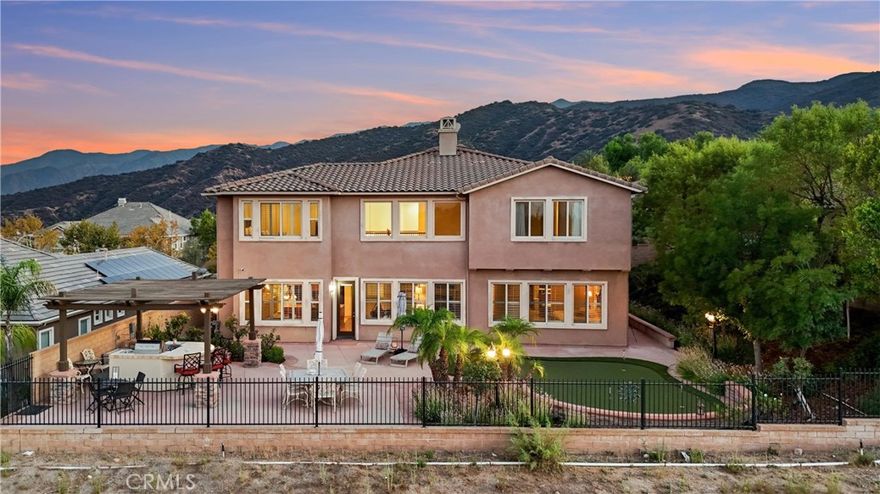 5 BEDROOMS (INCLUDING DOWNSTAIRS PRIMARY + 3 SUITES) | 3-CAR GARAGE | Welcome to this prestigious executive estate, nestled in the sought-after Retreat Community where privacy, elegance, and refined living define everyday life. Enter through the oversized private courtyard and step into the grand formal entry, where soaring ceilings, custom mosaic tile, art display niches, wood flooring, and a sweeping staircase set the tone for timeless sophistication. The open-concept Family Room is both inviting and refined, boasting a gas fireplace, custom drapes, plantation shutters, and seamless access to the backyard. The chef’s Kitchen is designed for the culinary enthusiast, featuring an oversized island with breakfast bar seating, pantry, granite countertops, stainless steel appliances, butler’s pantry, pot and pan drawers, and coffee station, all flowing into the formal Dining Room. French doors from the formal Dining Room open to front courtyard for effortless entertaining. A bonus Living Room offers versatility as a music room, office, or more gathering space. The main-level Primary Ensuite Bedroom is a true retreat, highlighted by coffered ceilings, private sitting area, and serene views. The spa-inspired Primary Ensuite Bathroom features dual vanities, a deep soaking tub, oversized walk-in shower with bench, make-up vanity, and a custom walk-in closet with center island. Upstairs, 4 additional bedrooms offer unparalleled comfort. Bedroom #2 is oversized with its own bathroom and walk-in closet. Bedroom #3 features French doors and a full bath with granite counters. Bedroom #4, currently an office, includes its own ensuite and private balcony with sunrise views. Bedroom #5 completes this wing, ideal for multi-generational living. A separate Laundry Room with sink, cabinetry, and folding station adds convenience. The backyard is an entertainer’s paradise, complete with custom hardscape, stone waterfall, artificial turf, four-hole putting green, built-in BBQ with sink, refrigerator, and bar seating, all framed by low Maintenace wrought iron and block fencing. ENERGY EFFICIENCY: Solar panels, recessed lighting, & ceiling fans add efficiency to unmatched elegance.  AMENITIES: Community pool, playground, basketball court, & fireplace. LOCATION: Quick access to 15 Expressway, 91 & 71 Freeways, & 241 Toll Road. This home is more than a residence—it’s a statement of luxury living.