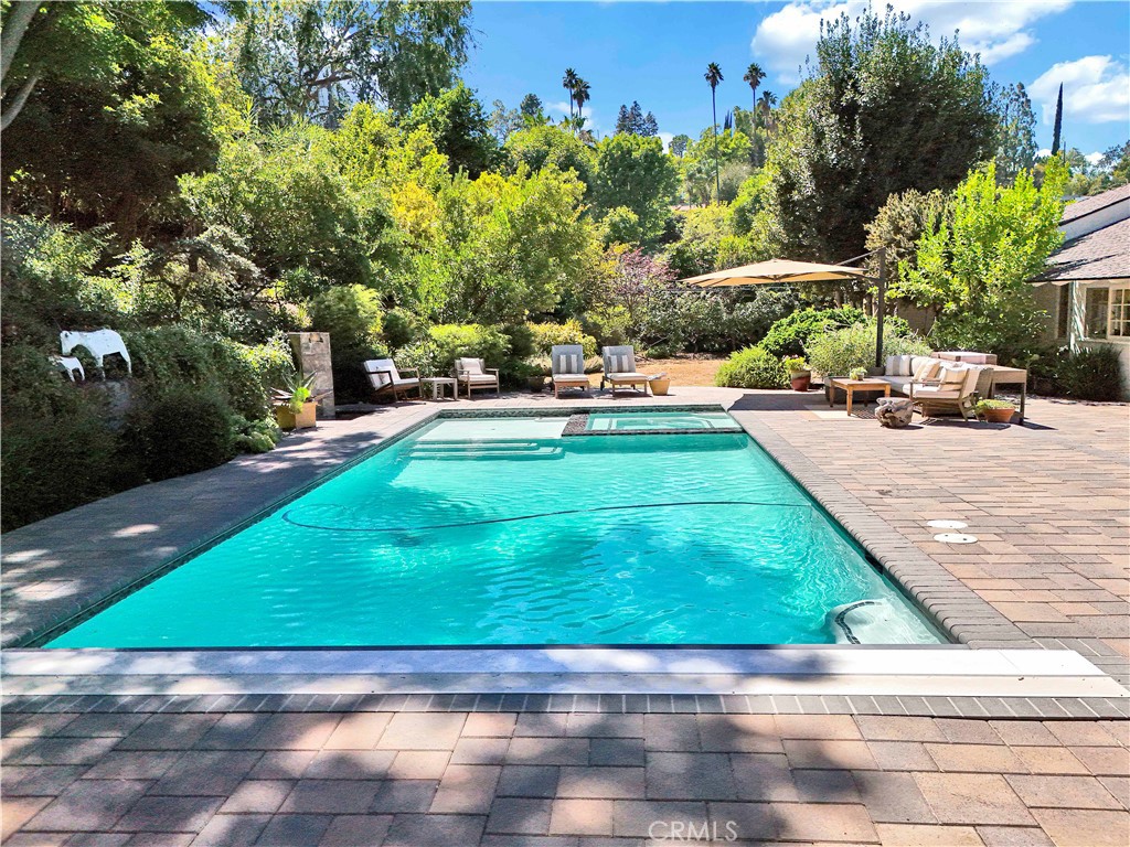 Welcome to 18090 Karen Drive! Nestled on an expansive 19,000+ sq. ft. lot. This modern ranch-style home is rich in character and charm. The spacious single-level layout offers a serene countryside feel, enhanced by large picture windows that frame breathtaking views of the lush greenery surrounding the property. Privacy and tranquility abound in this exceptional custom residence.
This thoughtfully designed home features a formal living room adorned with an oversized fireplace, creating a warm and inviting atmosphere. With four generously sized bedrooms, a cozy den complete with a fireplace, and multiple French doors leading to the backyard, this home is perfect for both relaxation and entertaining.
The primary suite is a true retreat, boasting a large walk-in closet, stunning views of the backyard, and a luxurious remodeled bath. The light-filled formal dining room flows seamlessly into the family-style kitchen, which is a chef's dream. This custom-made kitchen features abundant built-ins, an oversized center island, marble countertops, a custom skylight, a Wolf range, all complemented by a cozy eat-in area with French doors that open to the outside patio and a sunlit butler's pantry to conveniently keep all your gardening tools and party supplies.
Step outside to discover a professionally designed and landscaped backyard, complete with a newly constructed saltwater pool with custom electric cover, a magnificent waterfall, and a beautiful grassy area. The terraced slope leads to a flat pad large enough for the potential construction of a guest house. The eco-friendly yard boasts lush drought-tolerant plants, including lemon, pomegranate, quince and cumquat fruit trees. A wireless and remote entry enclosed dog run is located at the side of the house.
Enjoy alfresco dining and outdoor entertaining in this completely private and tranquil oasis! Don’t miss your chance to own this stunning residence, showcasing turnkey perfection and offering effortless living!