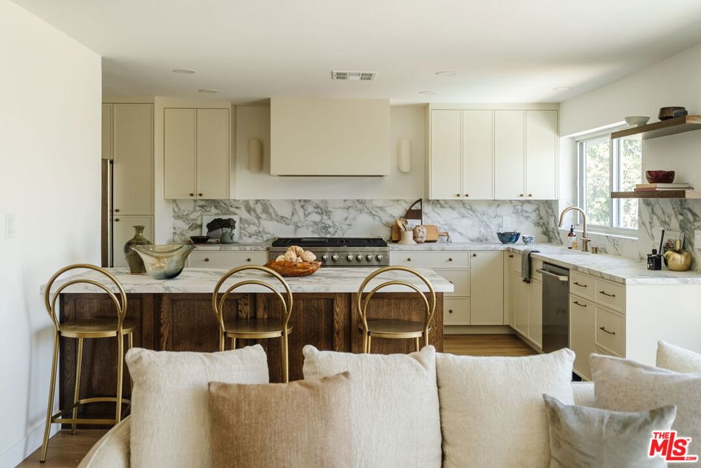 Reimagined with a relaxed, modern sensibility inspired by the California coast, this five-bedroom residence in Playa del Rey offers a warm, welcoming retreat infused with natural light, ocean breezes, and a floor plan that invites effortless living. Positioned on a quiet street just minutes from the beach, the home is surrounded by lush landscaping and filled with views that shift beautifully from sunrise to sunset. Expansive windows frame every space with natural light, while wood floors, brick fireplaces, and curated design touches add warmth and character throughout. The living room opens to a sunlit balcony -- an ideal setting for morning coffee, evening wind-downs, or simply soaking in the seabreeze. Just beyond, the gourmet kitchen is outfitted with premium appliances, including a double-oven range, and connects seamlessly to the dining area and family room, creating a fluid hub for gathering. Stunning stone countertops and backsplash add sophistication, while a seated peninsula offers everyday functionality with an inviting spot to cook, connect, or entertain. Four bedrooms are situated on the main level, inclusive of the primary suite with a spacious walk-in closet, and the final bedroom is downstairs. Each room feels bright and airy, shaped by sunlight and the soft rhythm of coastal living. On the lower level, a family room opens to the backyard and offers effortless versatility -- whether used as a media lounge, home gym, game room, or creative studio. Outside, the private backyard is a true extension of the home -- featuring a sparkling pool and generous covered and uncovered patio space for lounging, dining al fresco, and entertaining under the open sky. Moments away from local restaurants, boutiques, the Ballona Creek Bike Path, and the beach, this is a home designed for modern coastal living -- where every day moves a little easier and life is always sweet.