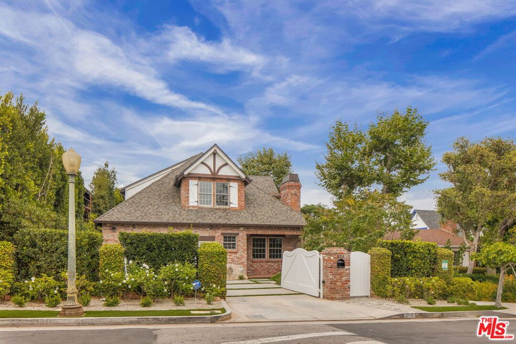 Set behind gates on an expansive flat lot in a coveted Brentwood neighborhood, this enchanting brick Tudor blends timeless character with refined livability. Upon entering, the home's architectural pedigree is on full display -- beamed and coffered ceilings, intricate moldings, and ornate stone fireplaces lend warmth and sophistication. The light and bright floorplan flows effortlessly from the formal living and dining rooms into a window-lined great room. Here, a family room offers access to a covered brick patio with a wood-burning fireplace, and the adjacent, chef-inspired kitchen is ideal for entertaining. The kitchen is set around a seated center island, outfitted with built-in Viking appliances and ample pantry storage, including a butler's pantry with prep sink. A library with built-ins in rich wood tones brings the sophistication of an executive suite home. The expansive floorplan offers six ensuite bedrooms providing flexibility and comfort, including two primary suites: one on the main level and one upstairs. The upstairs primary retreat is a true haven with a sitting room, private balcony overlooking the lush garden, dual walk-in closets, and a bath with dual vanities and a separate tub and shower. A powder bath serves guests on the main level, while a versatile third-floor hideaway -- with full bath and peaked ceilings -- offers many possibilities as a playroom, office, or media lounge. Outdoors, the hedge-lined grounds are designed for both relaxation and entertaining, featuring a vast turf lawn, sparkling pool, and a pool house with a full bath. A built-in BBQ and multiple covered patios create inviting spaces for alfresco dining, while mature landscaping ensures beauty and privacy. All just moments from Brentwood Country Club, the Country Mart, the Farmer's Market, and San Vicente's fine dining and boutiques -- and minutes from the beach -- this estate is the embodiment of Westside living.
