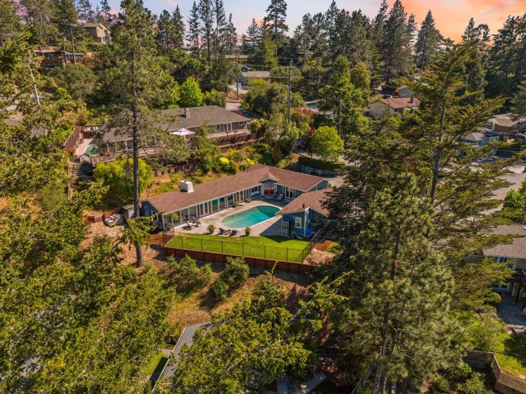 Welcome to your own private oasis in the heart of the sought-after Whispering Pines neighborhood. Located on a quiet cul-de-sac, this turnkey 4 bed/3 bath home, complete with a beautifully finished detached ADU offers the ideal setup for multi-generational living, extended guests, or additional rental income. The main residence is designed for connection and comfort, featuring an open-concept layout filled with natural light, vaulted ceilings, floor-to-ceiling windows, and a cozy gas fireplace. French doors throughout the home create a seamless indoor-outdoor flow to a sunny patio and resort-style pool, perfect for entertaining or relaxing with guests. The spacious primary suite opens directly to the pool deck, offering a private space for peaceful mornings or starlit evenings. The detached ADU provides a fully private and thoughtfully designed living space, ideal for multi-generational living or even as a rental. Complete with its own entrance, the ADU is a versatile gem that truly expands the way you live. Surrounded by trees yet close to everything, enjoy easy access to local shops, hiking trails, farmers' markets, and cozy cafes, plus a quick drive to Santa Cruz beaches or the Bay Area.