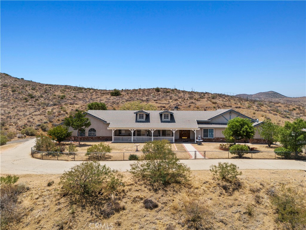 INCREDIBLE OPPORTUNITY ON 3+ PRIVATE ACRES WITH ENDLESS POTENTIAL! Bring your imagination and vision—this spacious single-story home is ready to be transformed into your dream retreat! Nestled on over three acres in a peaceful setting with mountain views and privacy, the possibilities here are truly endless. Whether you're dreaming of a workshop, a pool and outdoor entertaining space, animal zoning, or simply wide-open tranquility, this blank canvas has the space to bring it all to life! Inside, the home is well-maintained and filled with natural light and timeless charm. The formal living and dining areas flow into the heart of the home: a warm and inviting family room with striking vaulted wood-beam ceilings and tongue-and-groove planks that exude rustic character. A floor-to-ceiling brick fireplace with bold herringbone detailing adds vintage appeal and cozy ambiance. The kitchen offers generous storage, wood cabinetry, recessed lighting, a center island with built-in cooktop, double ovens, and backyard views. Off the kitchen, a large laundry room includes additional cabinetry, counter space, a utility sink, plus direct outdoor access. Spacious primary suite features vaulted ceilings, double door access outside, ample closet space, plus an ensuite bathroom with dual vanities, soaking tub with views, and separate shower. Three secondary bedrooms and office offer great size and flexibility. Attached 3-car garage. Ample parking for RVs, boats, and more! Expansive front and backyards await your creativity. NO HOA, plus paved roads and public (county) water service! A rare chance to own land, privacy, and space! Come tour this one-of-a-kind property with incredible forever views and see the potential for yourself!